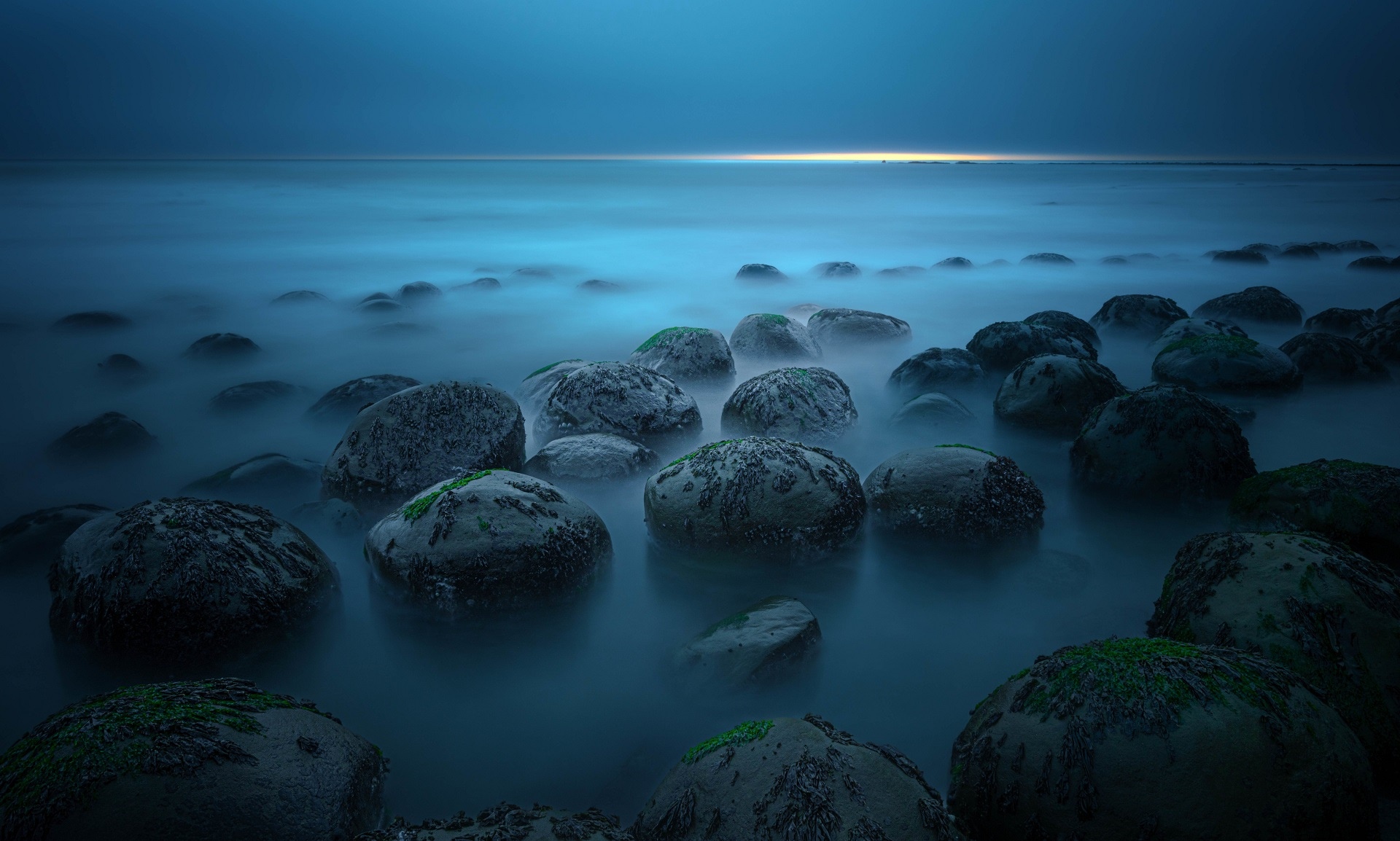 Rocks in the ocean with mist at dusk HD Wallpaper