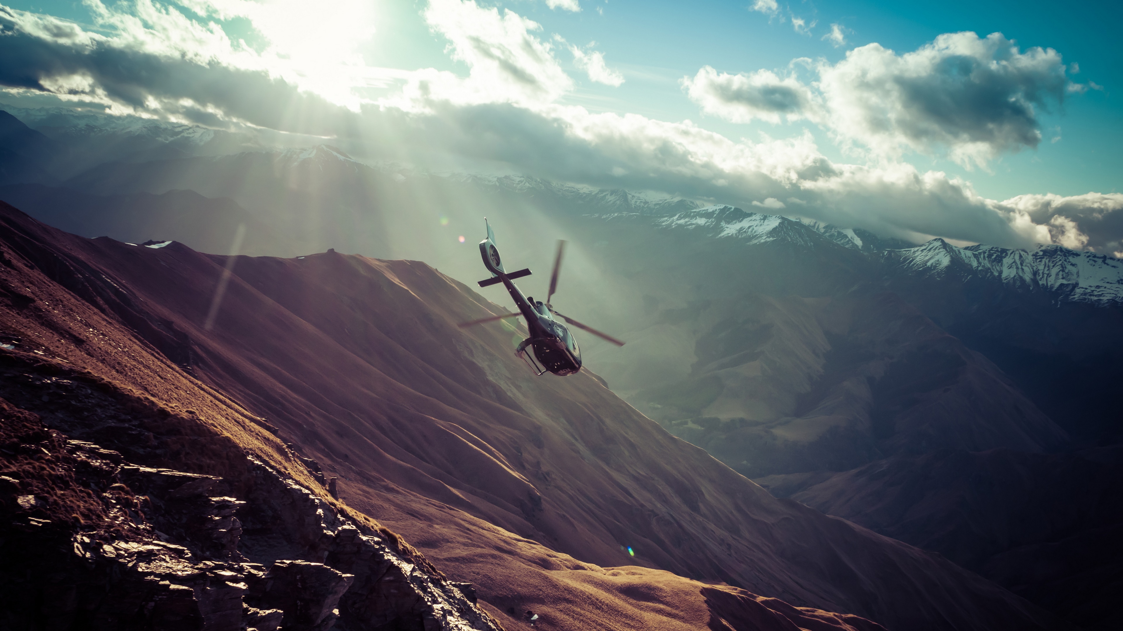 Helicopter flying over mountains with sunlight HD Wallpaper