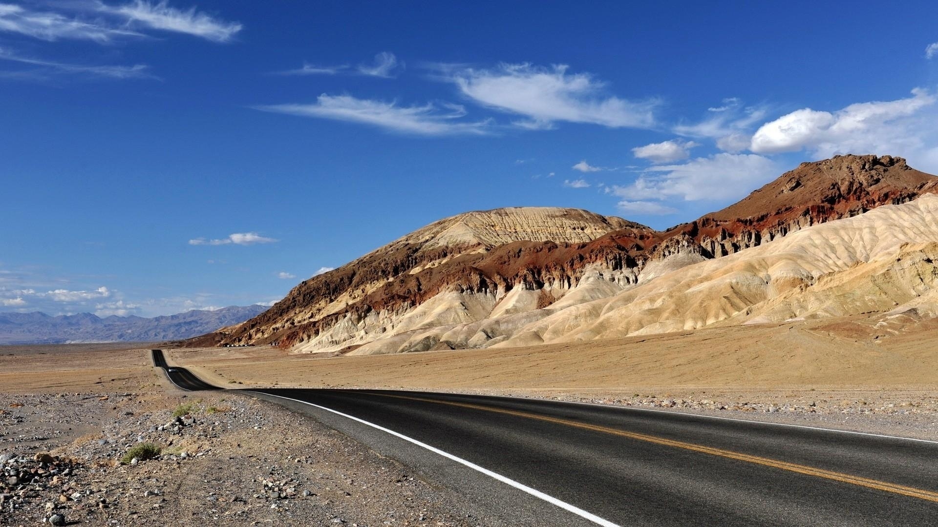 Road through colorful mountains under a blue sky HD Wallpaper