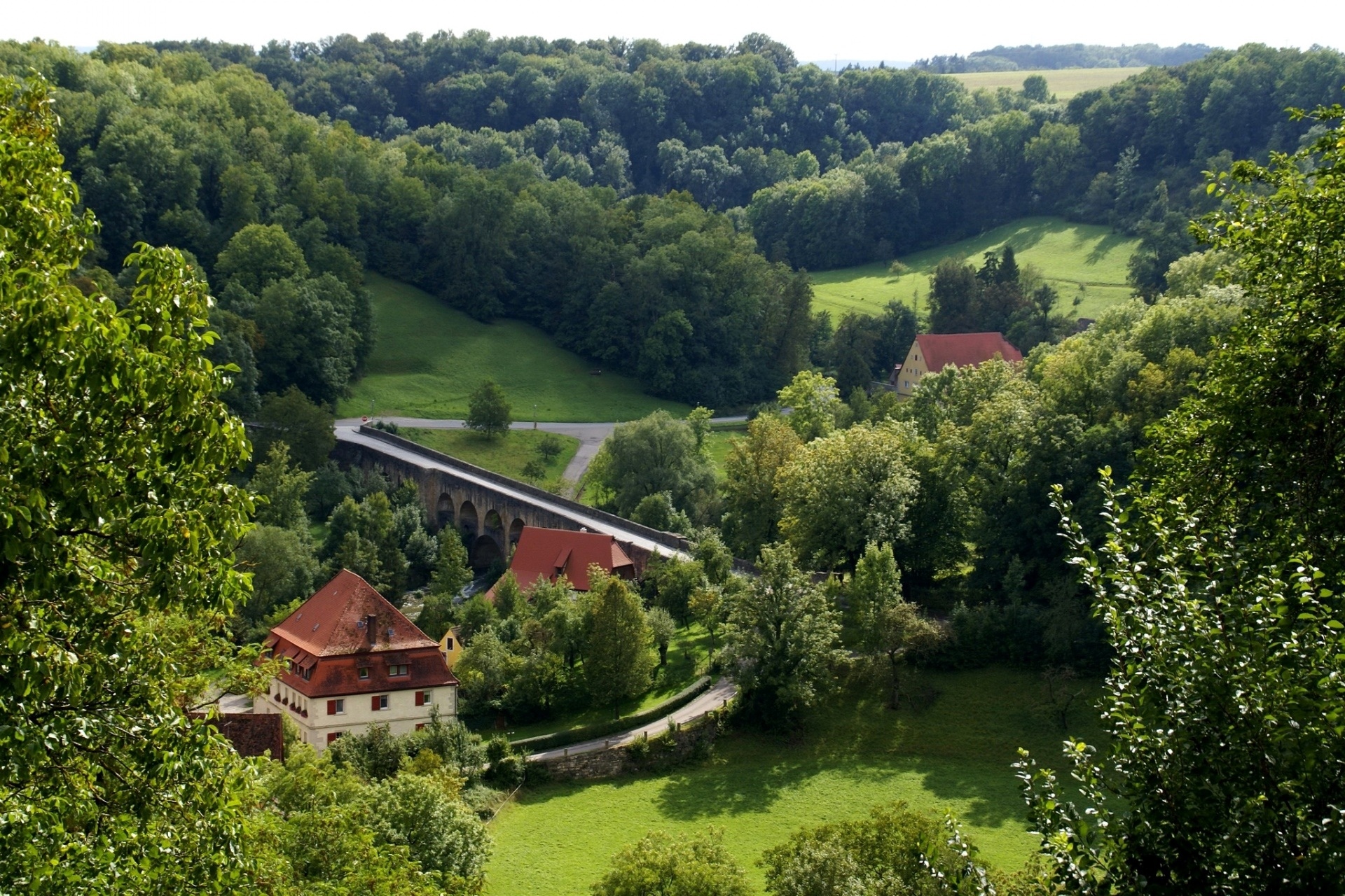 Arched bridge over a valley with houses and forests HD Wallpaper