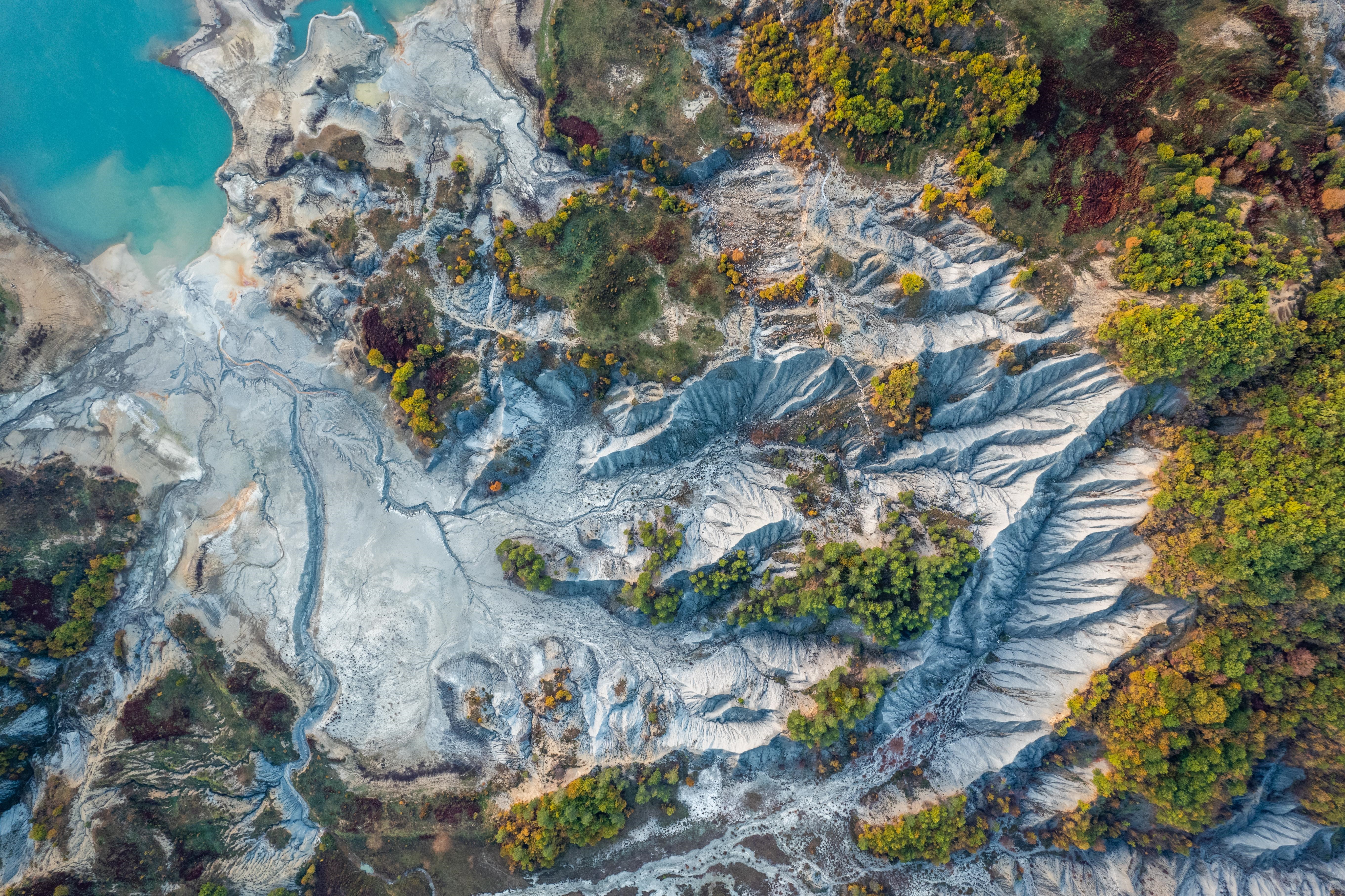 Aerial view of a barren landscape with a turquoise lake HD Wallpaper