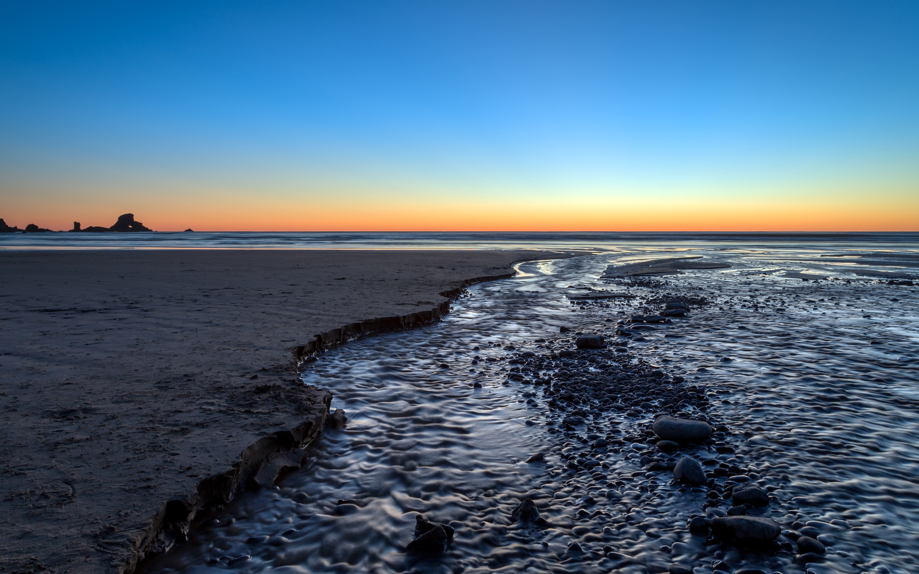 4K sunset glow over a beach with a stream HD Wallpaper