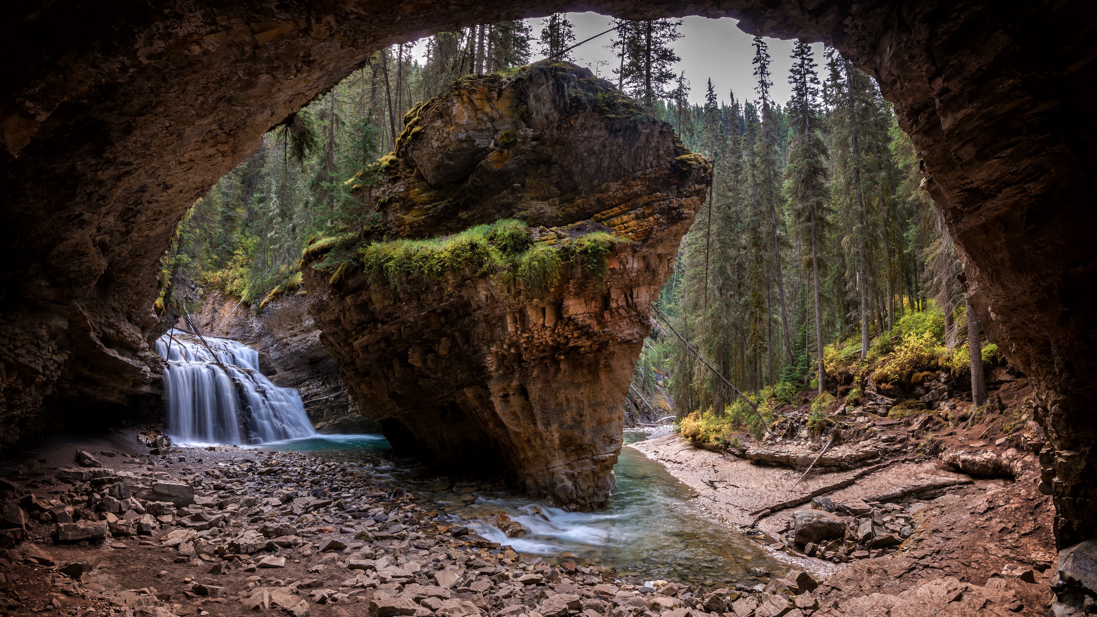 Cave entrance with waterfall and rock formation in forest HD Wallpaper