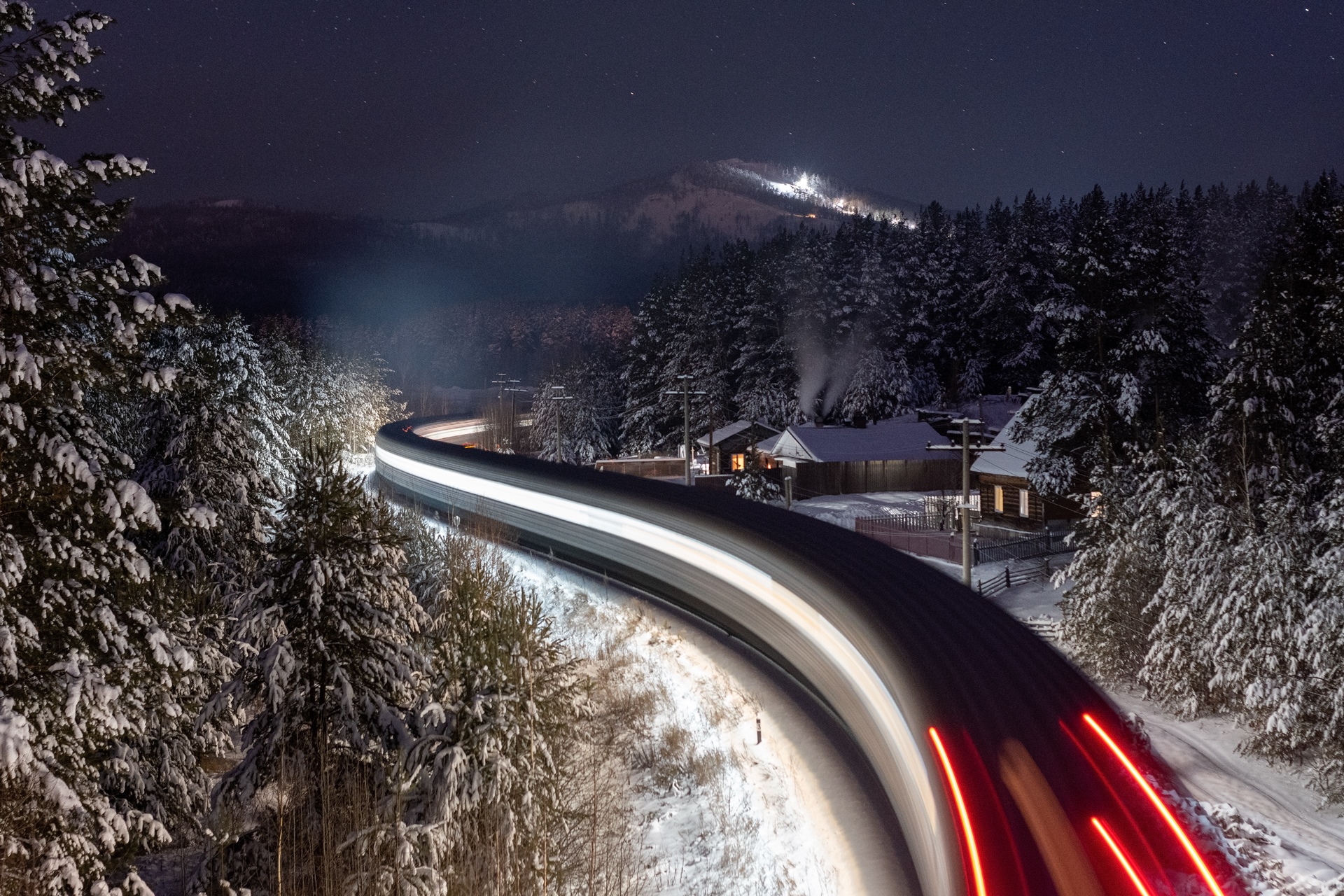 Train moving through a snowy forest at night HD Wallpaper