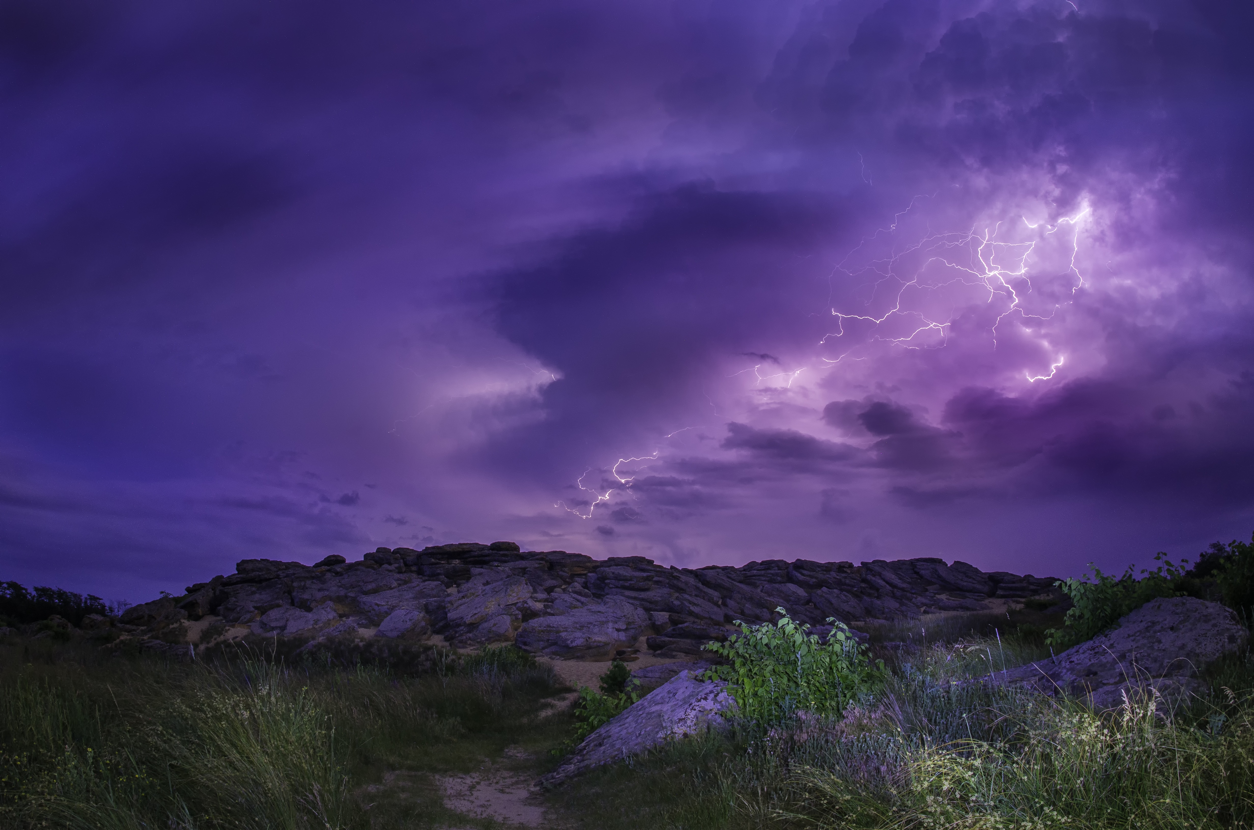 Thunderstorm with lightning over rocky terrain HD Wallpaper