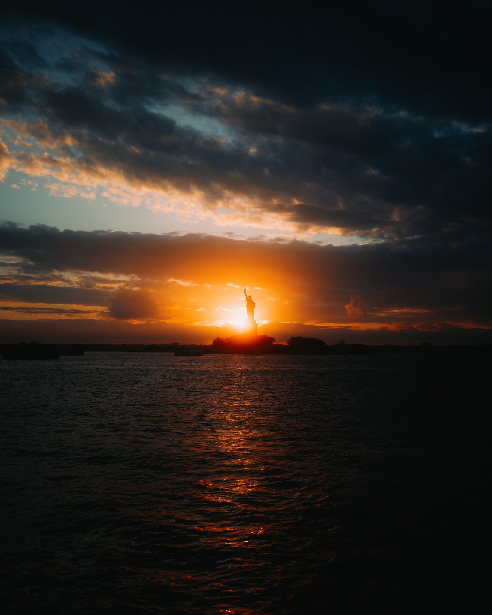 Statue of Liberty at sunset over water HD Phone Wallpaper