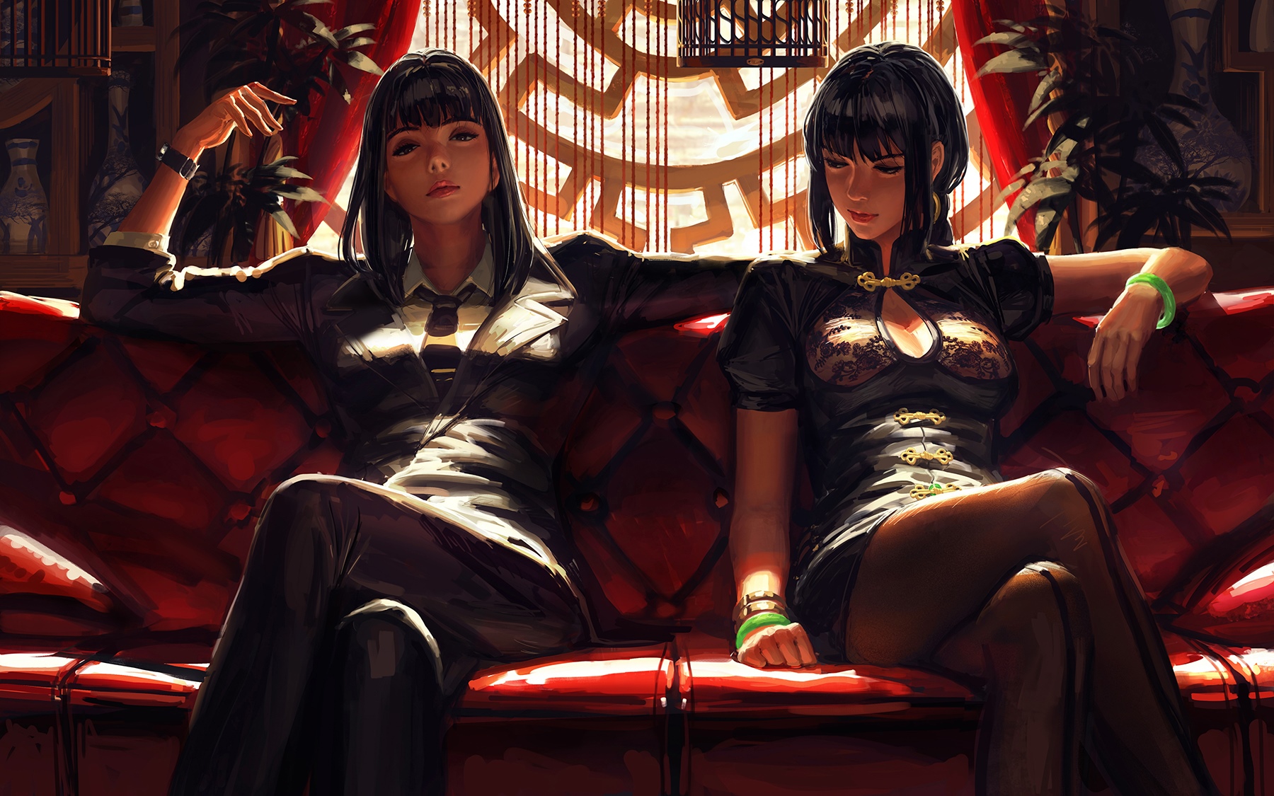 Two women in traditional and modern attire on a red couch HD Wallpaper