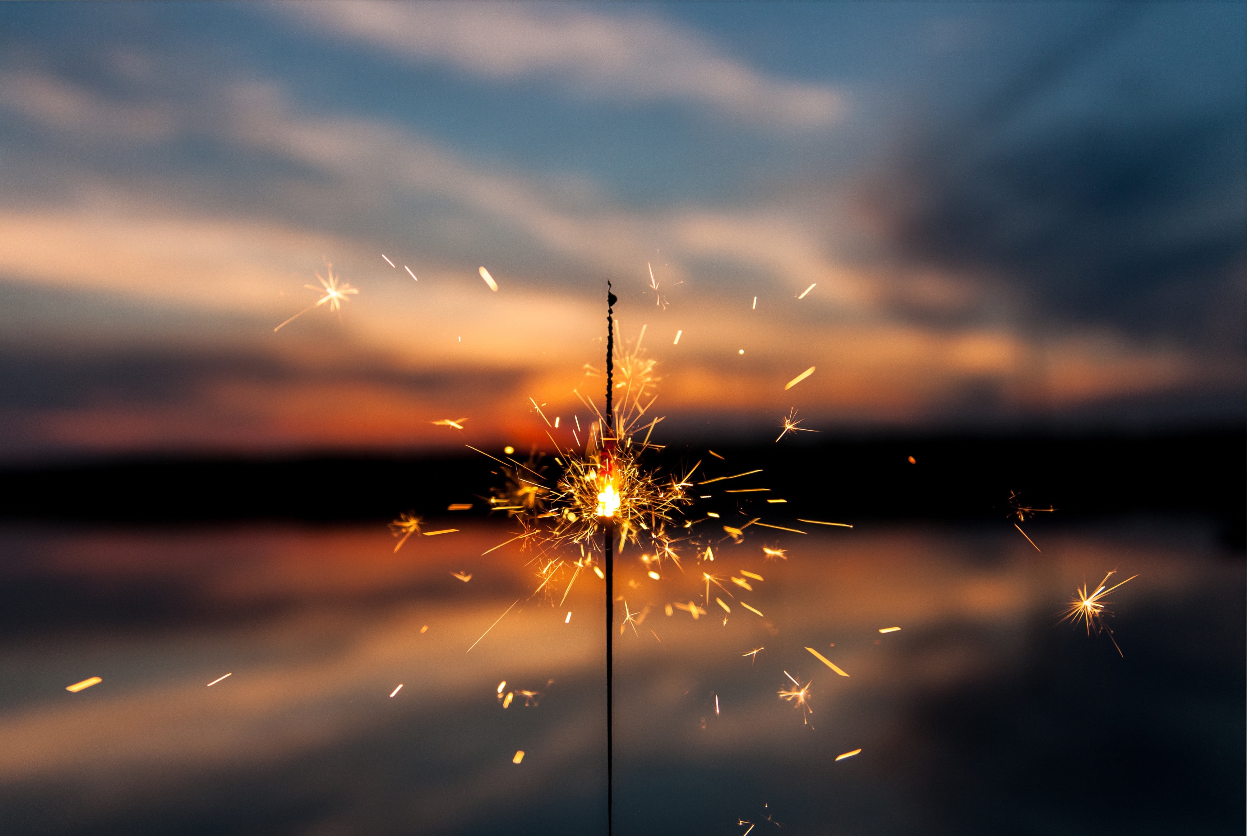 Sparkler against a sunset sky with clouds HD Wallpaper