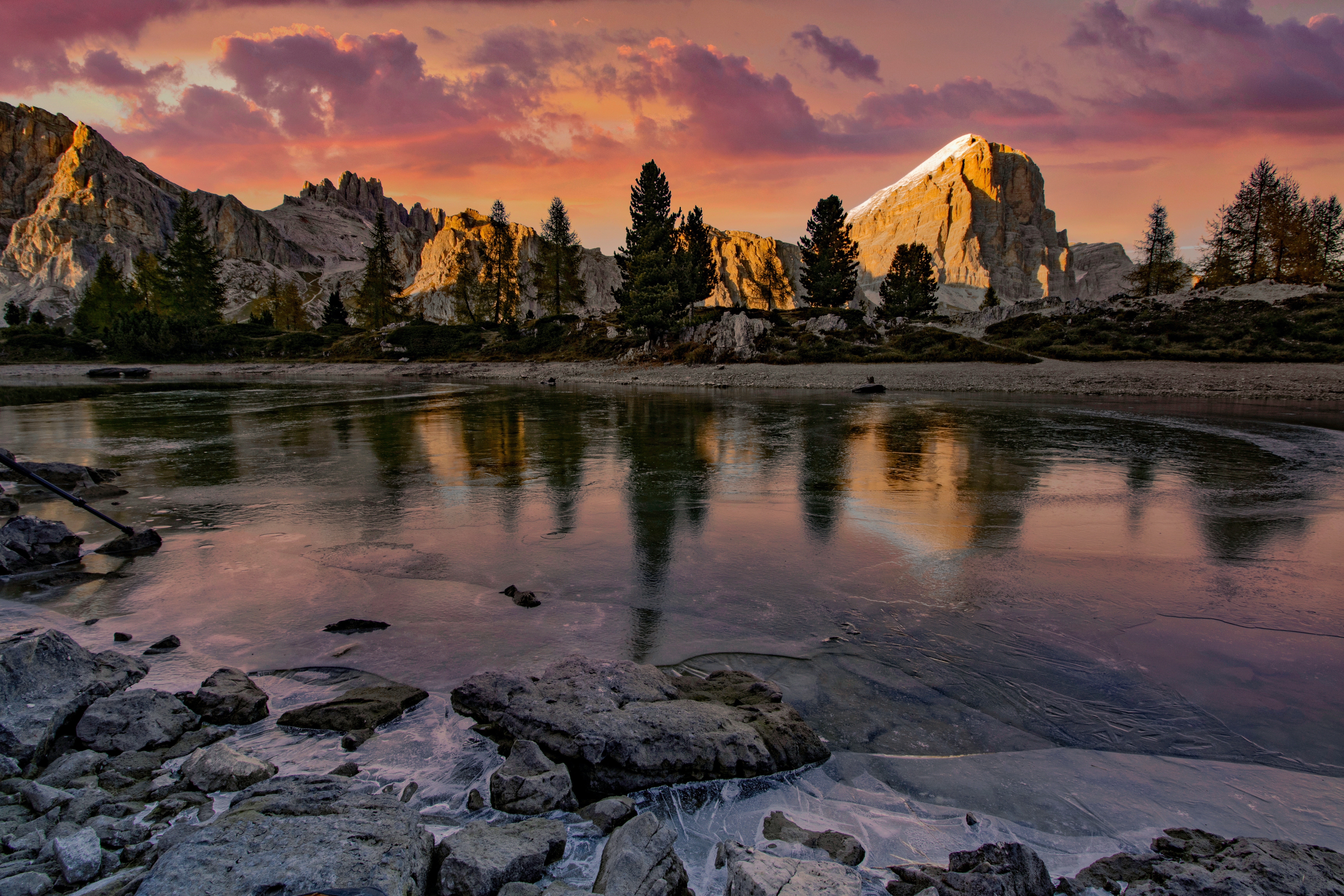 Mountains reflected in a frozen lake at sunset HD Wallpaper