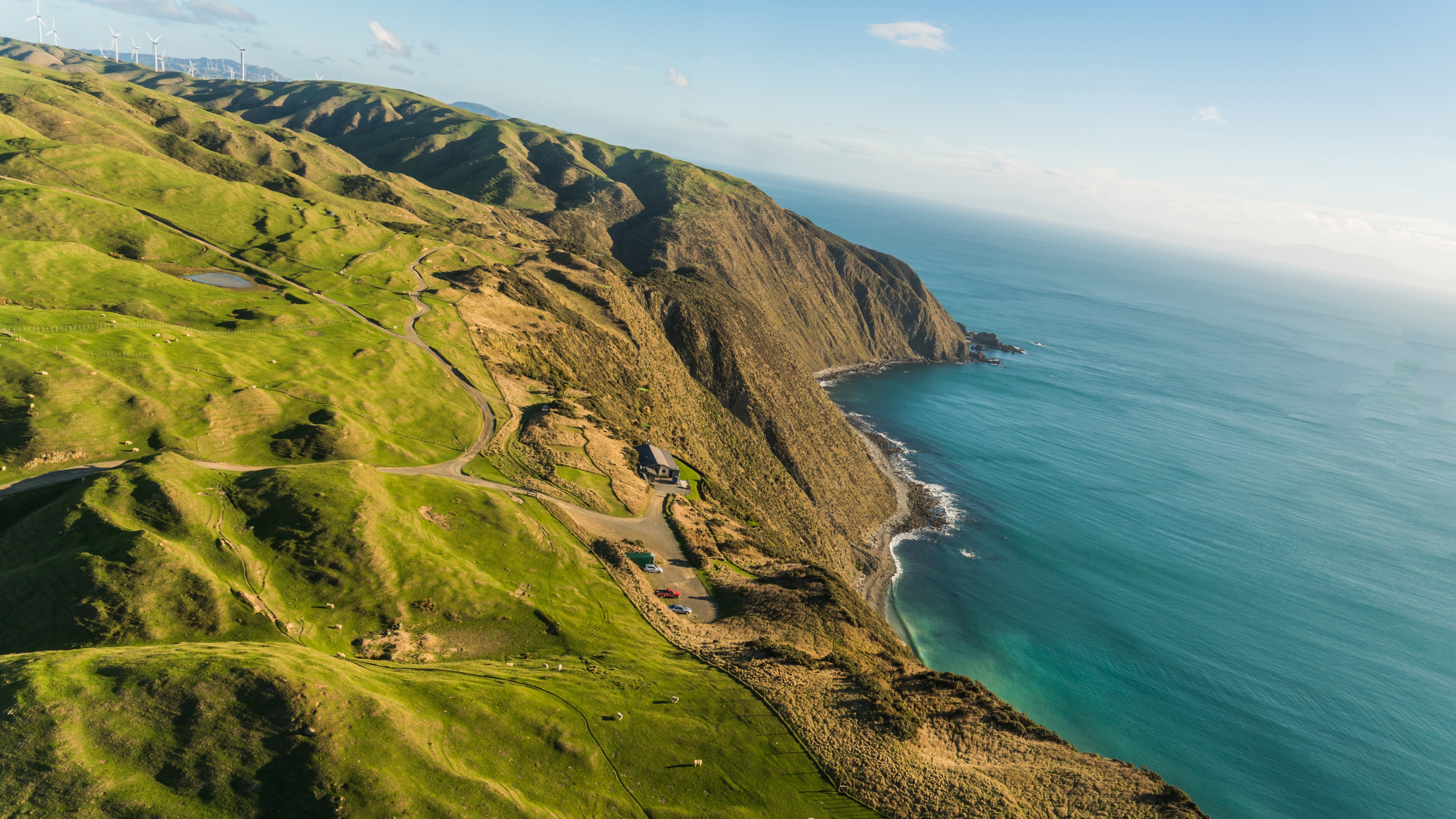 Wind turbines on rolling green hills by the sea in New Zealand HD Wallpaper