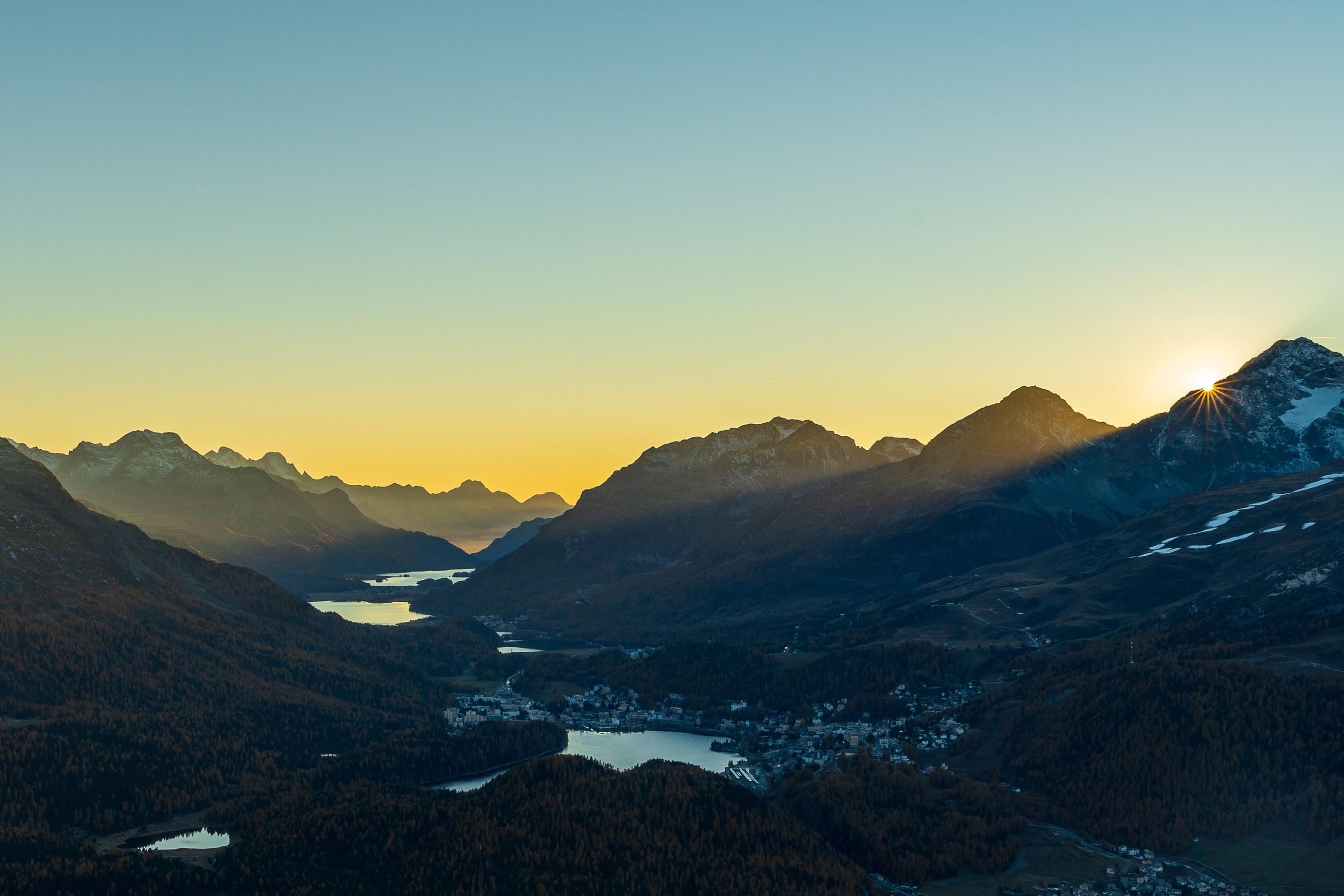 Sunset over mountains and lakes with a town HD Wallpaper
