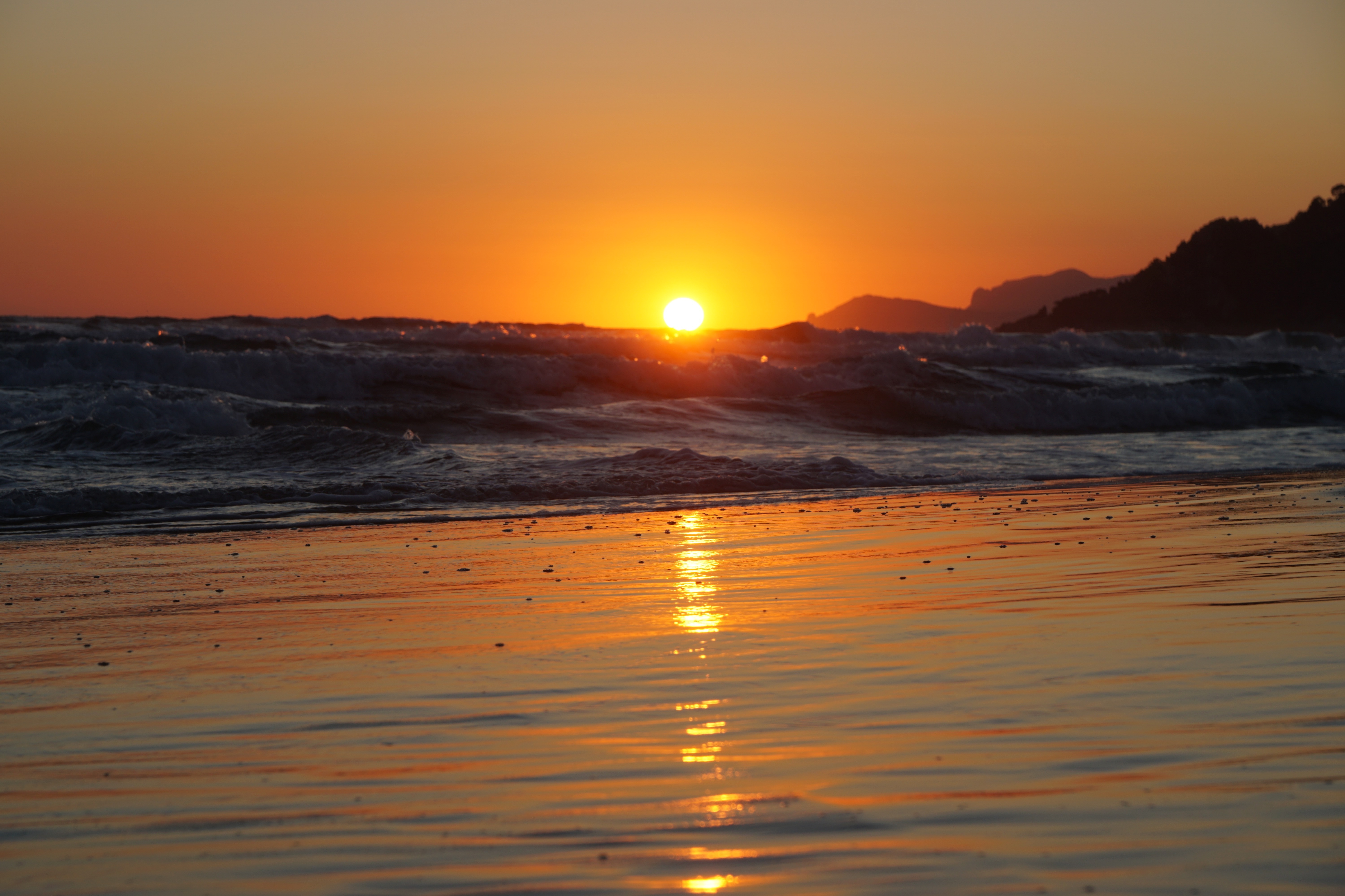 Sunset over the sea with mountains and waves HD Wallpaper