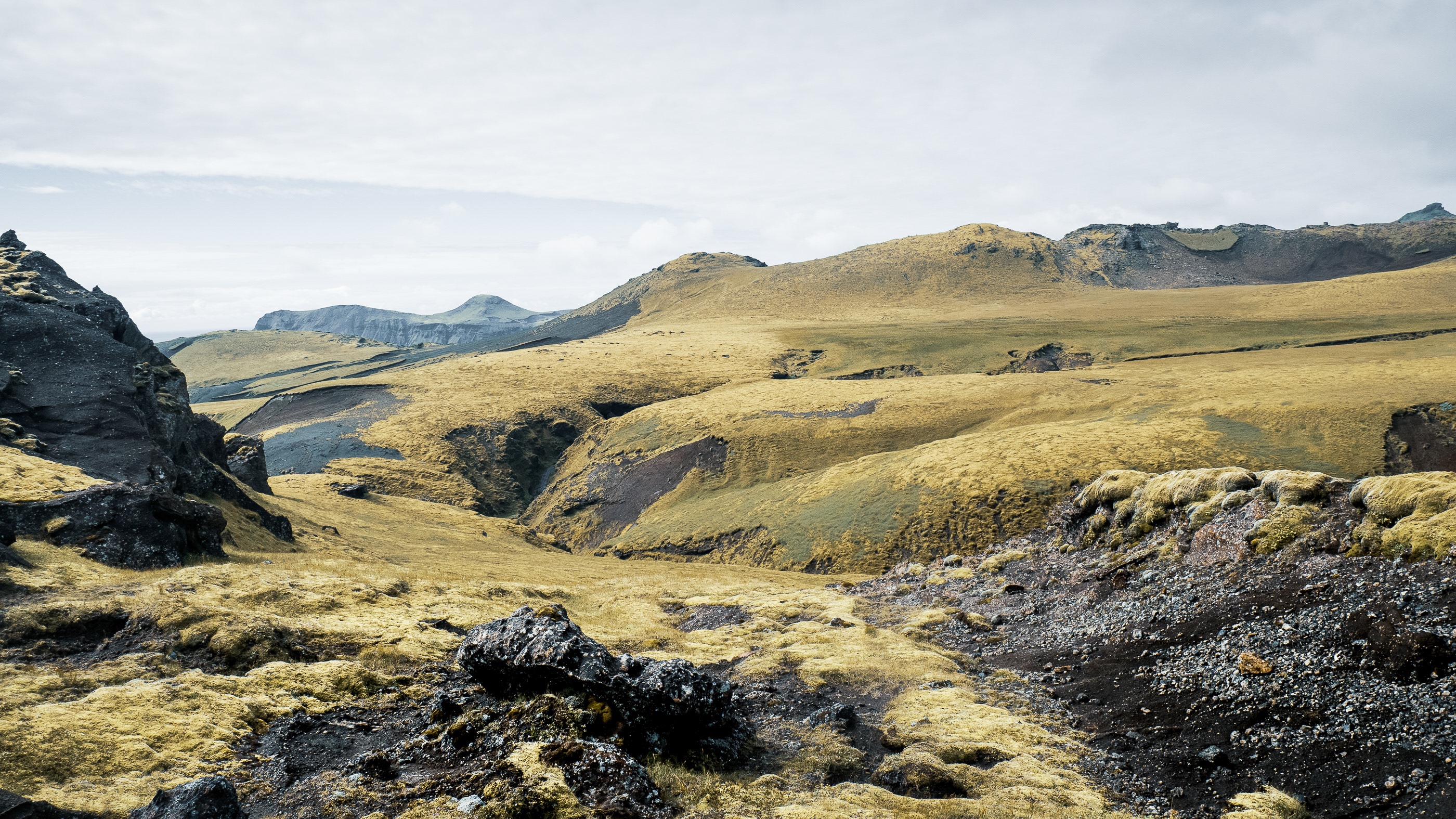 Icelandic landscape with rolling hills and rock formations HD Wallpaper
