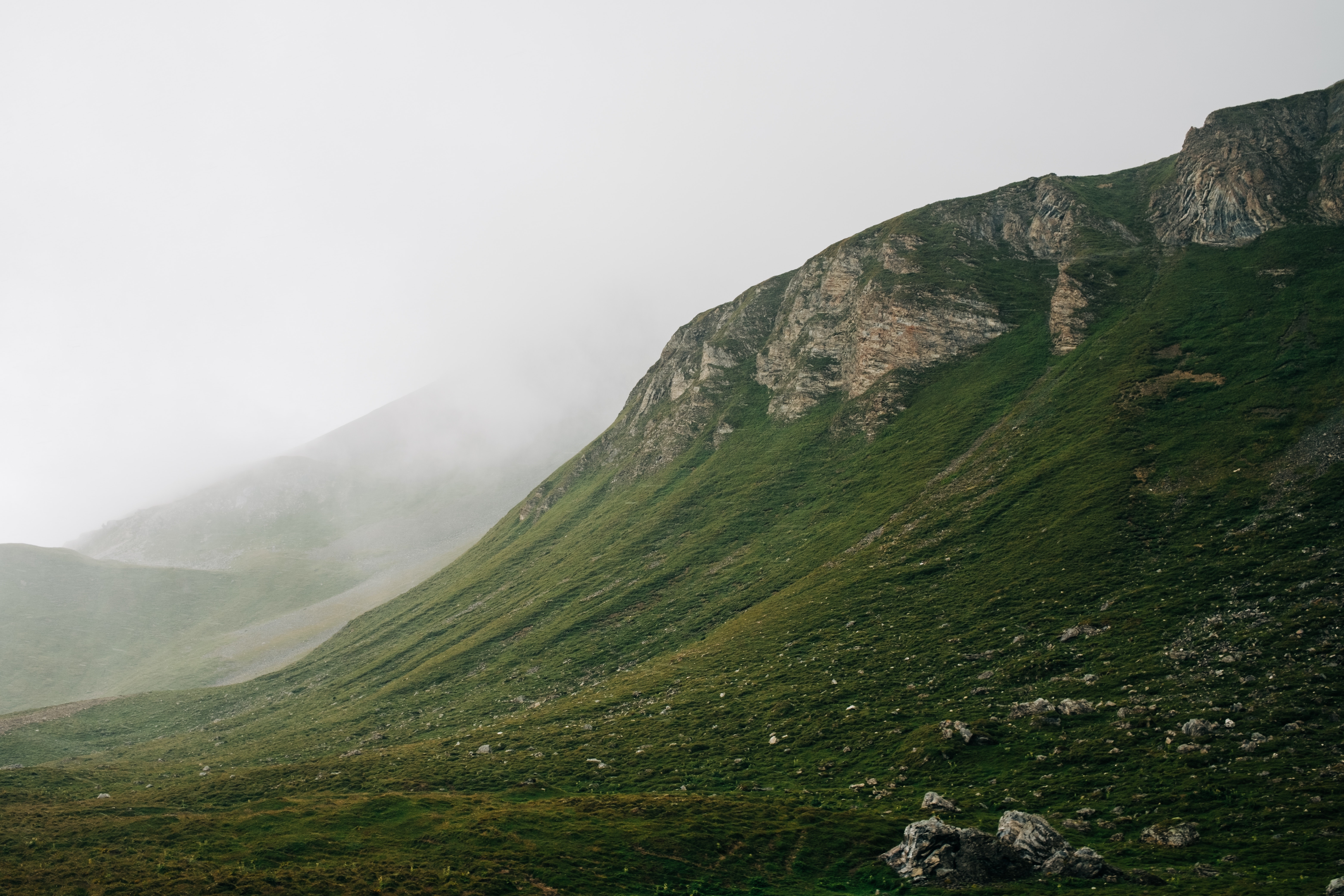 Misty mountains with green grass and rocks HD Wallpaper