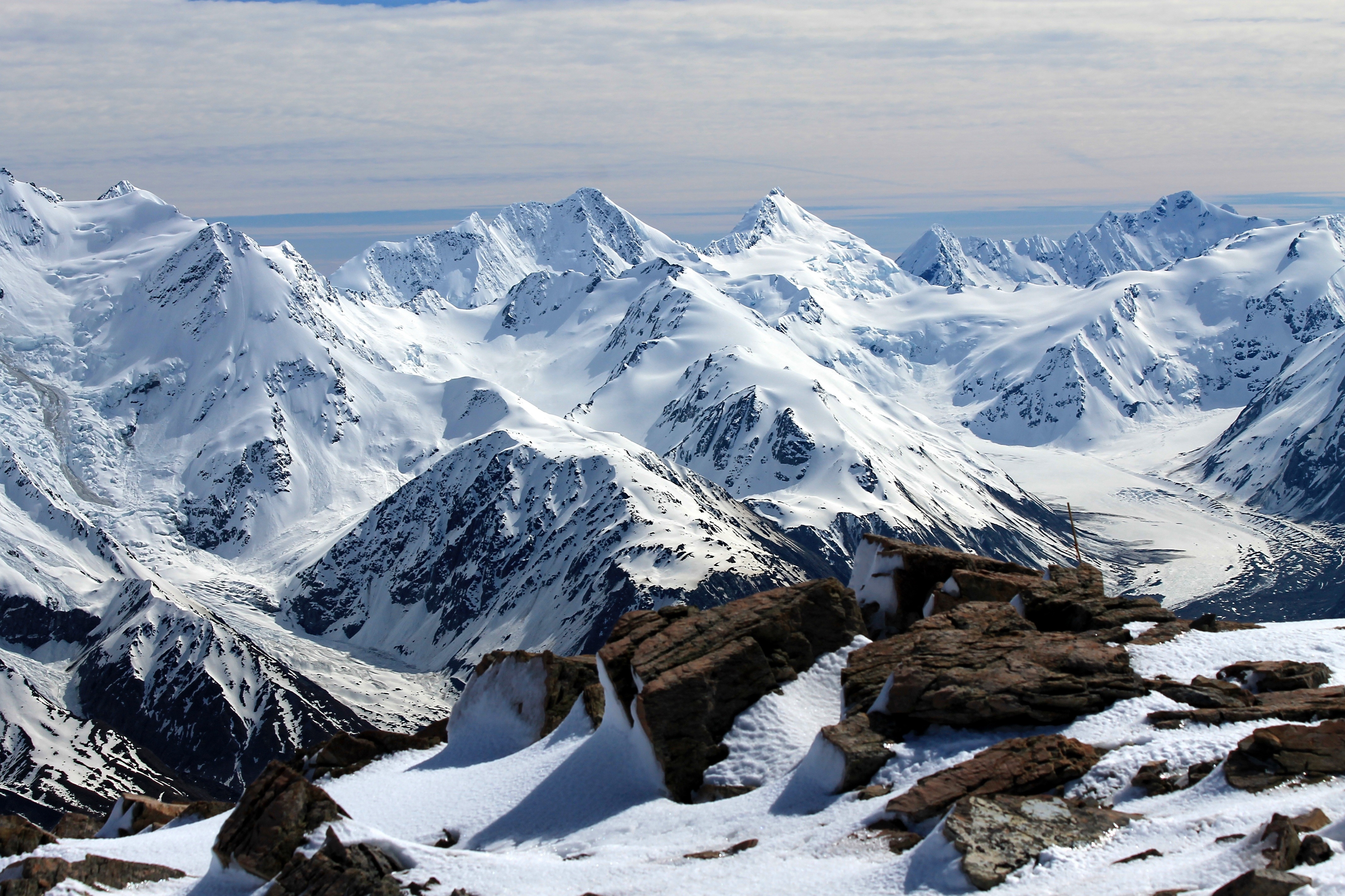 Snowy mountain peaks under a cloudy sky HD Wallpaper