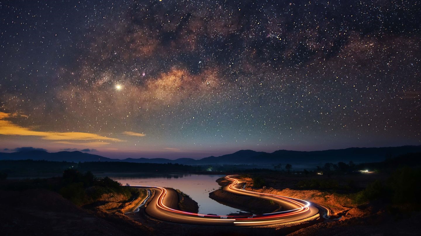 Road with light trails under a starry night sky HD Wallpaper