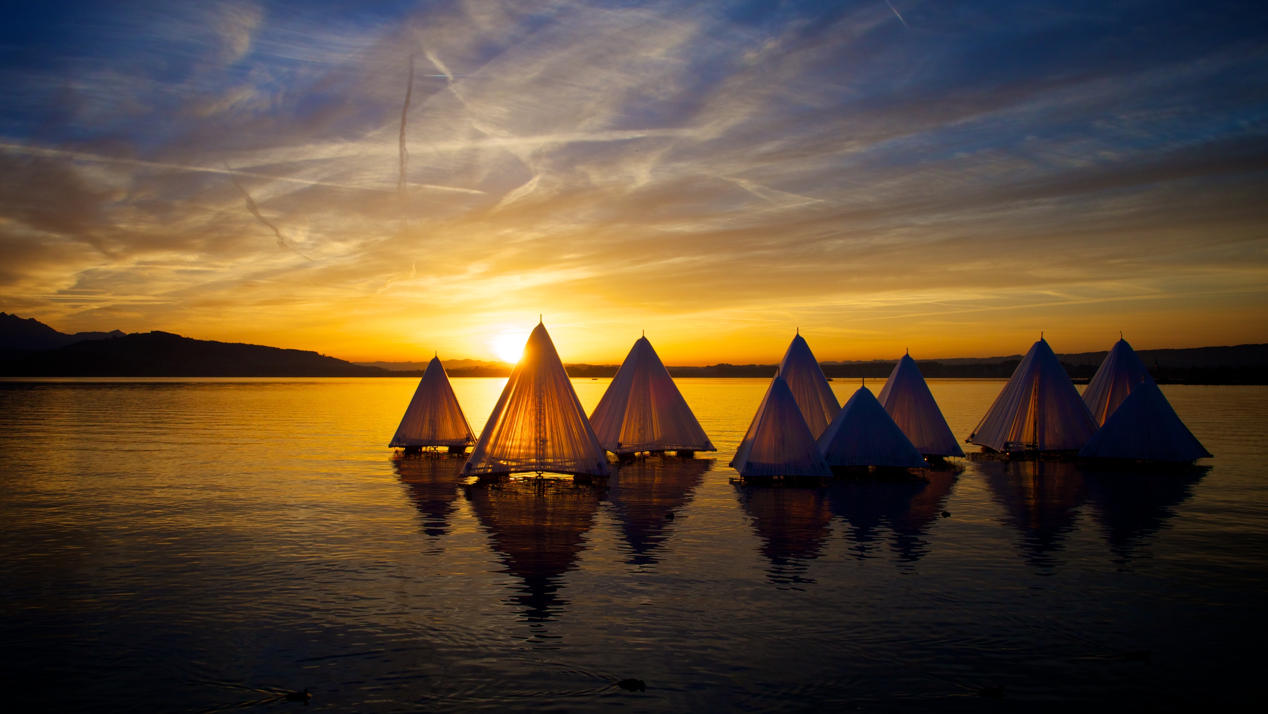 Boats on a lake at sunset with mountains HD Wallpaper