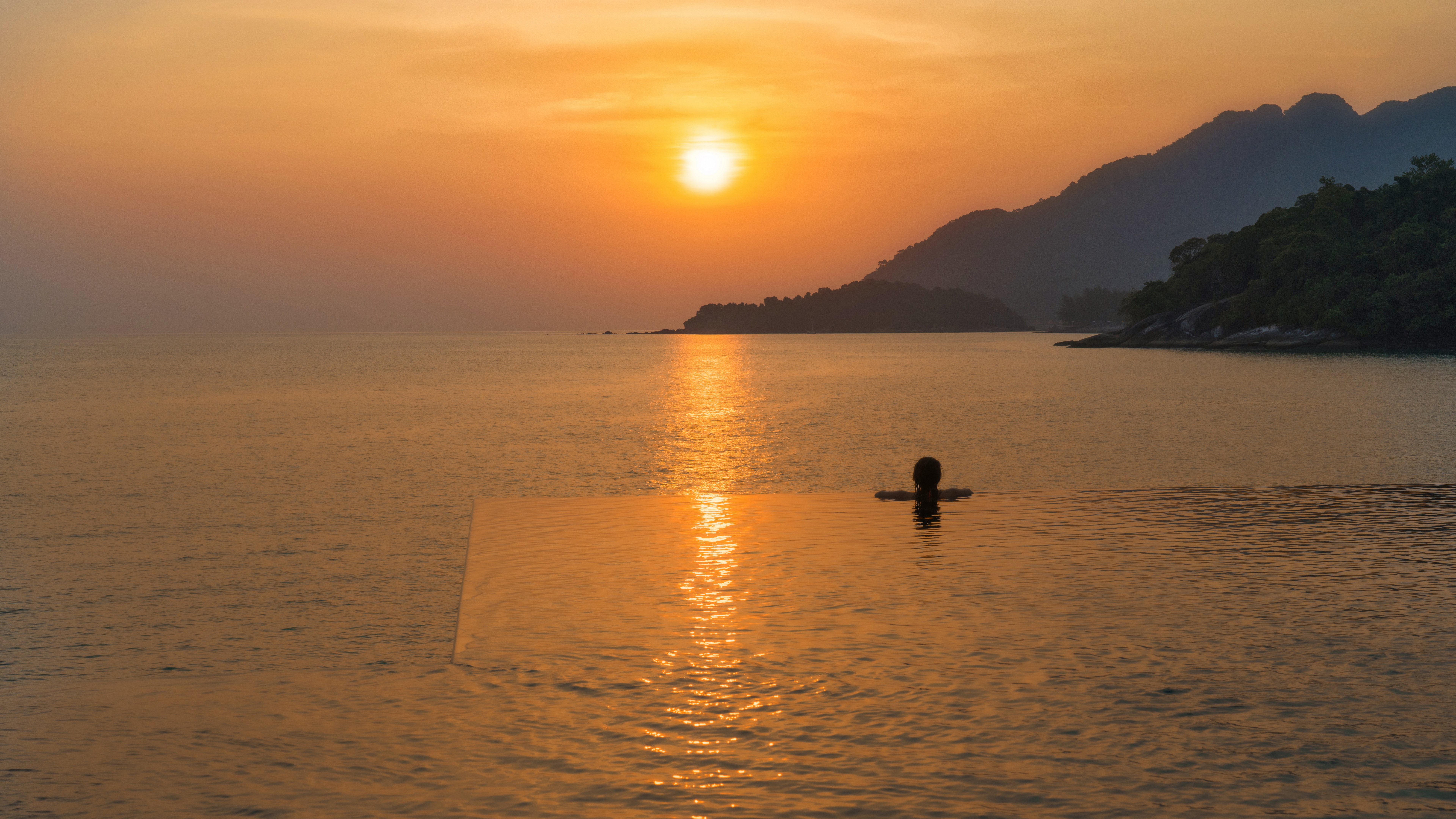 4K sunset over the ocean with person in infinity pool HD Wallpaper