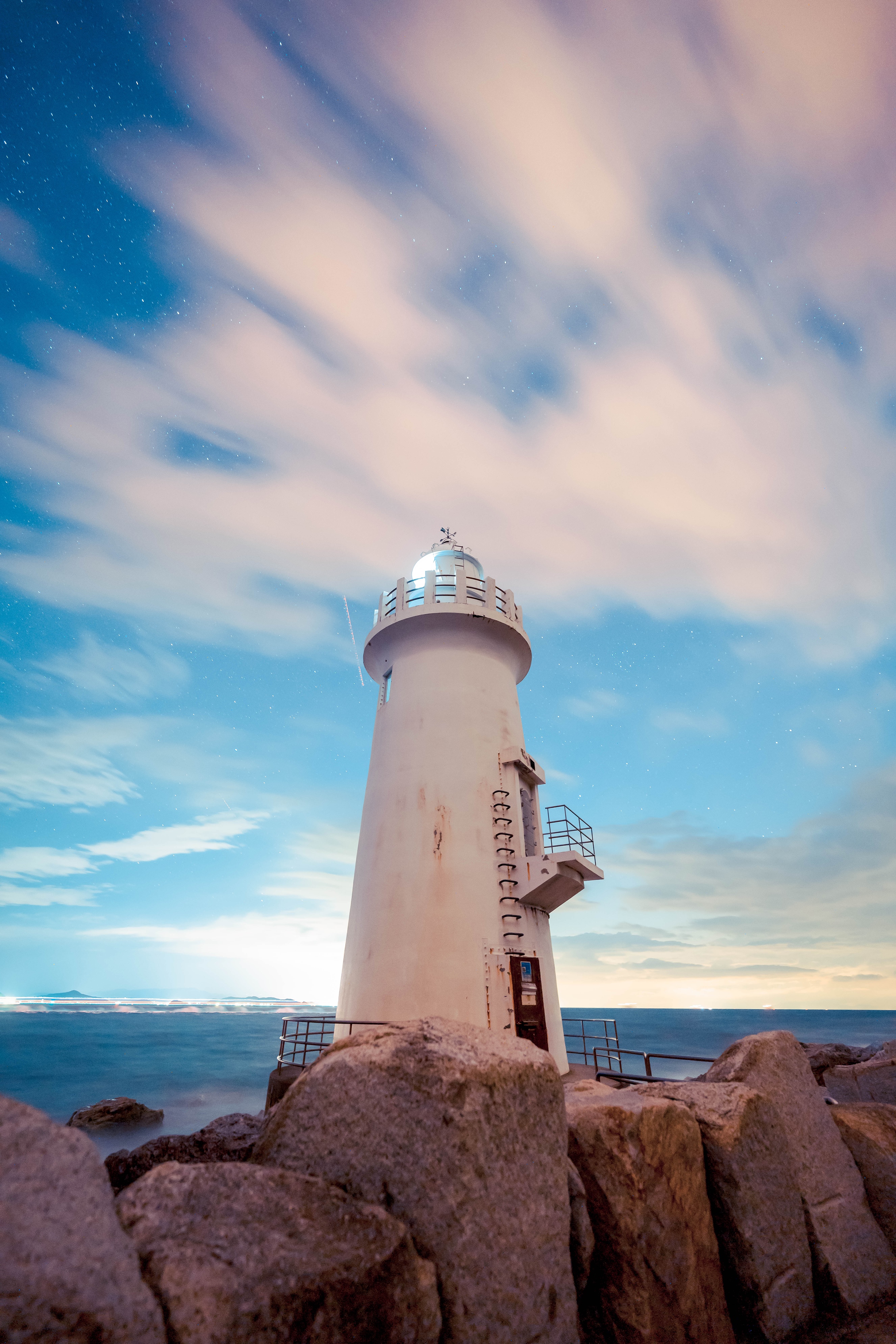 White lighthouse on rocks under starry sky HD Phone Wallpaper