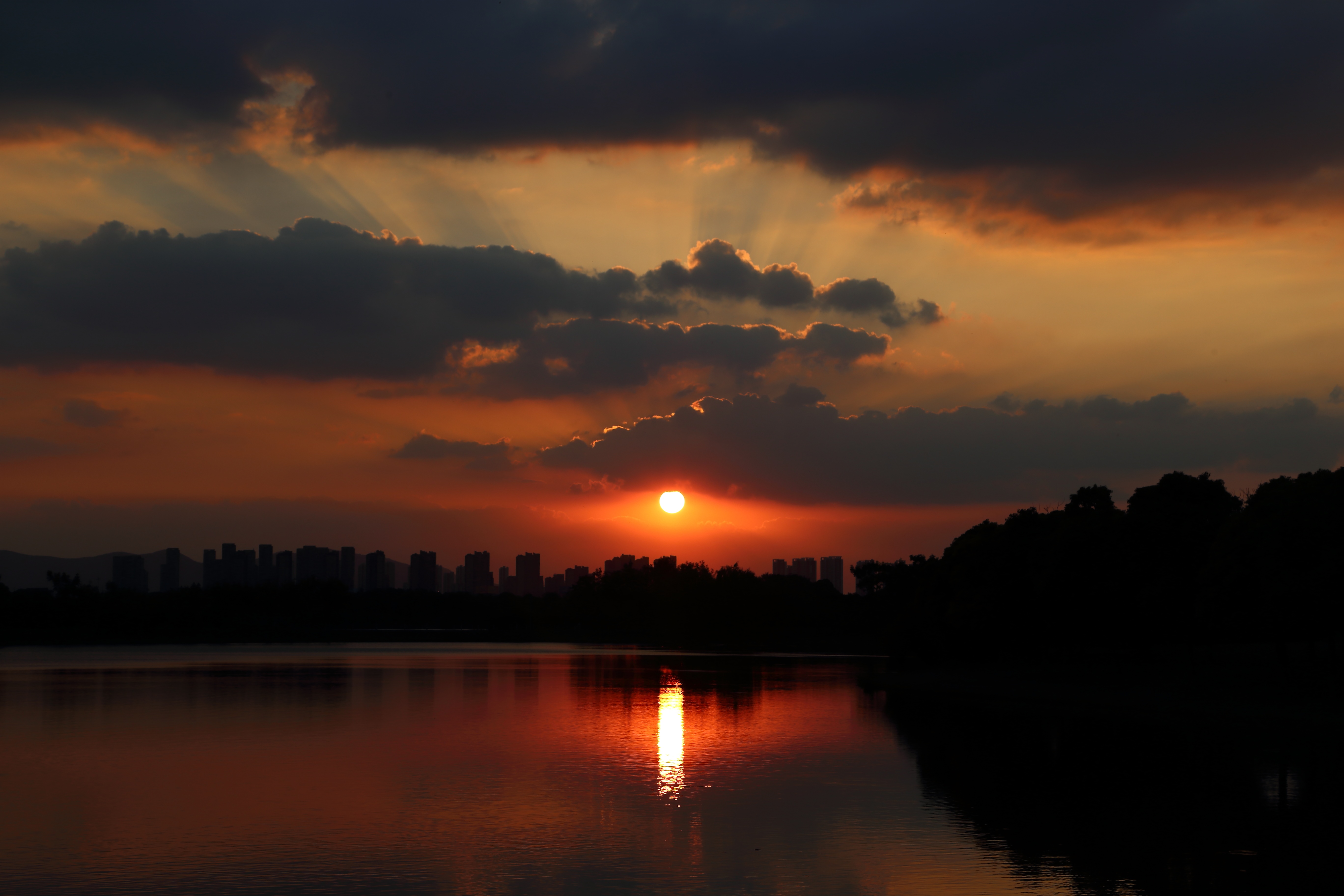 Sunset over a city skyline reflected in water HD Wallpaper