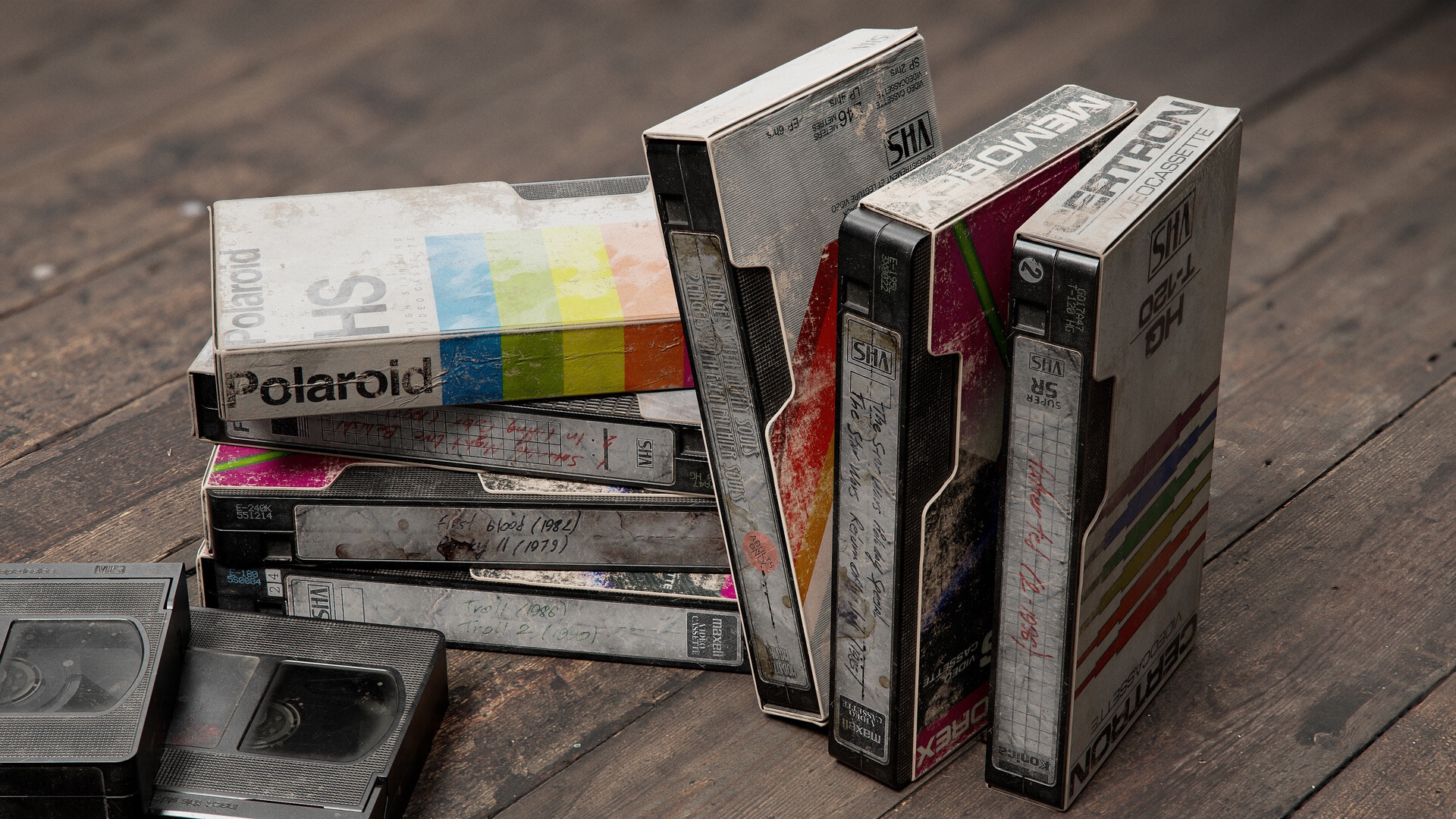 Stack of old VHS tapes on wooden surface HD Wallpaper