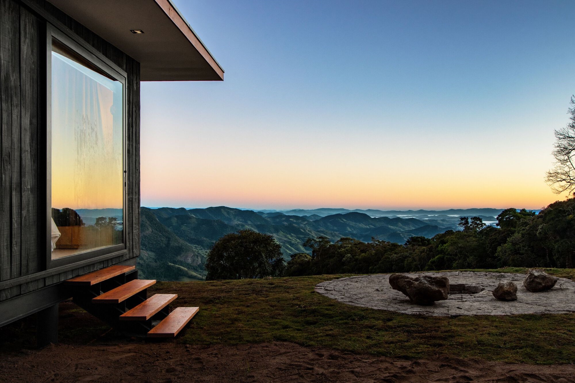 Modern cabin overlooking a mountain landscape at sunset HD Wallpaper