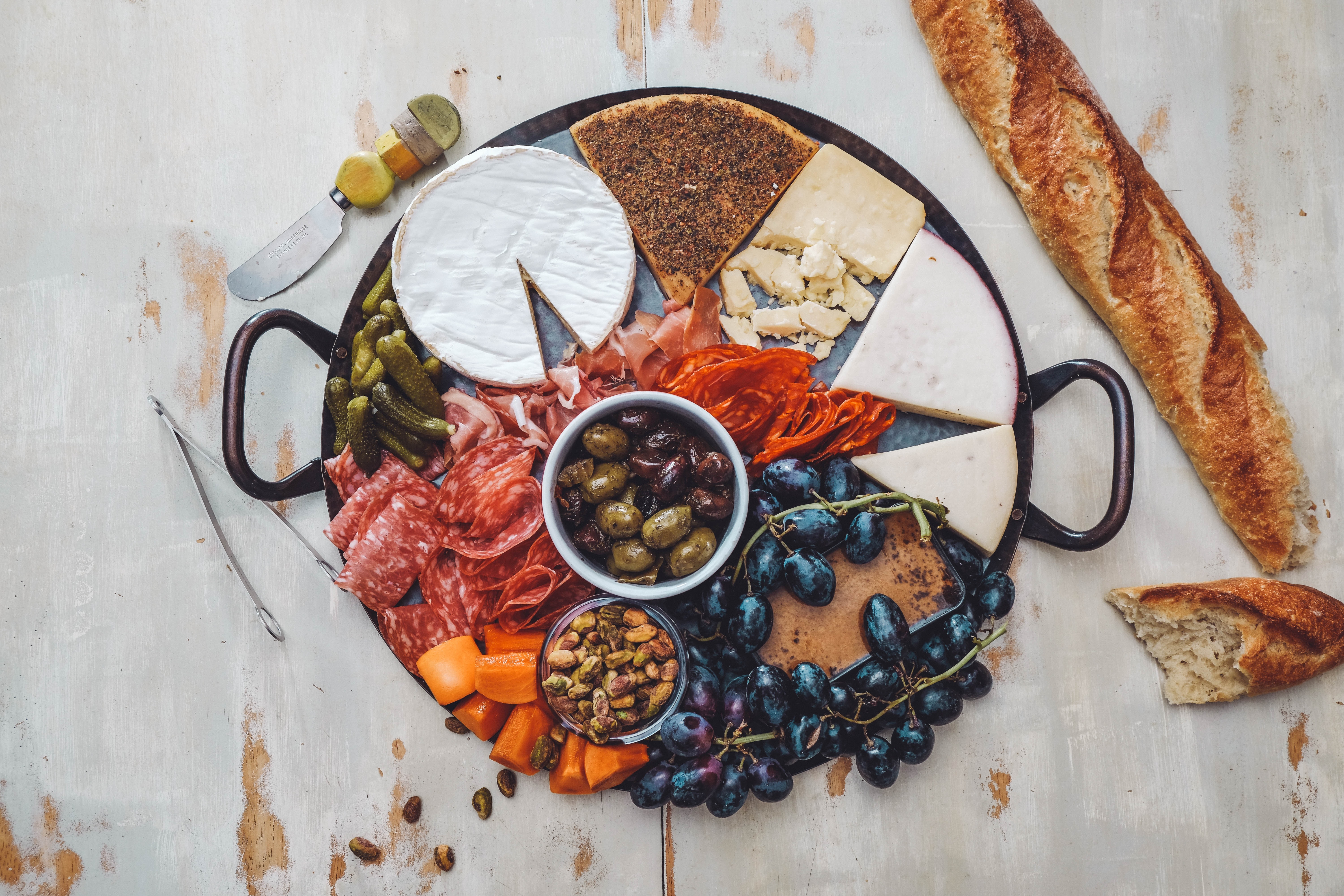 Charcuterie board with cheese, salami, olives, grapes, and bread HD Wallpaper