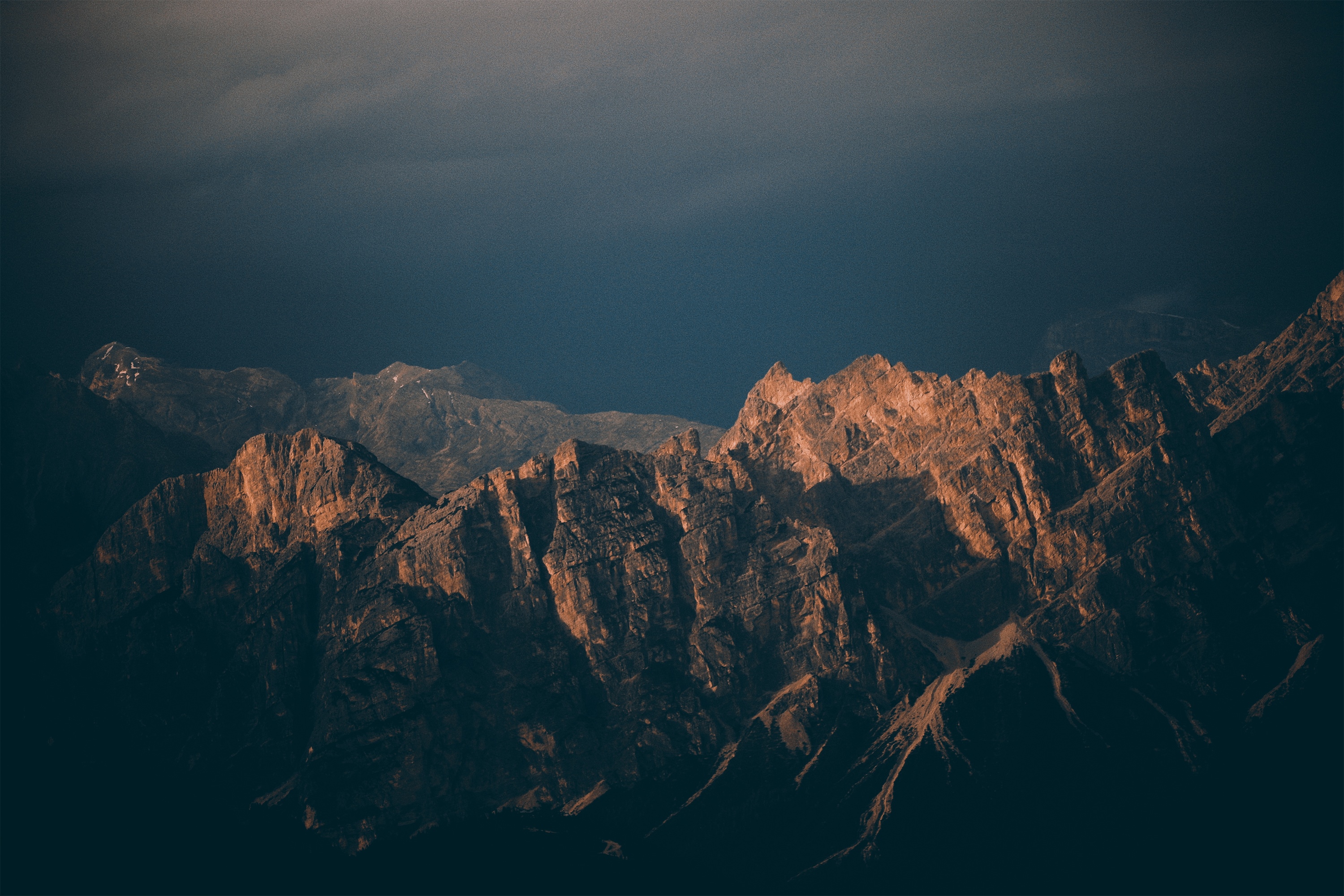 Jagged mountain range illuminated by golden sunlight HD Wallpaper