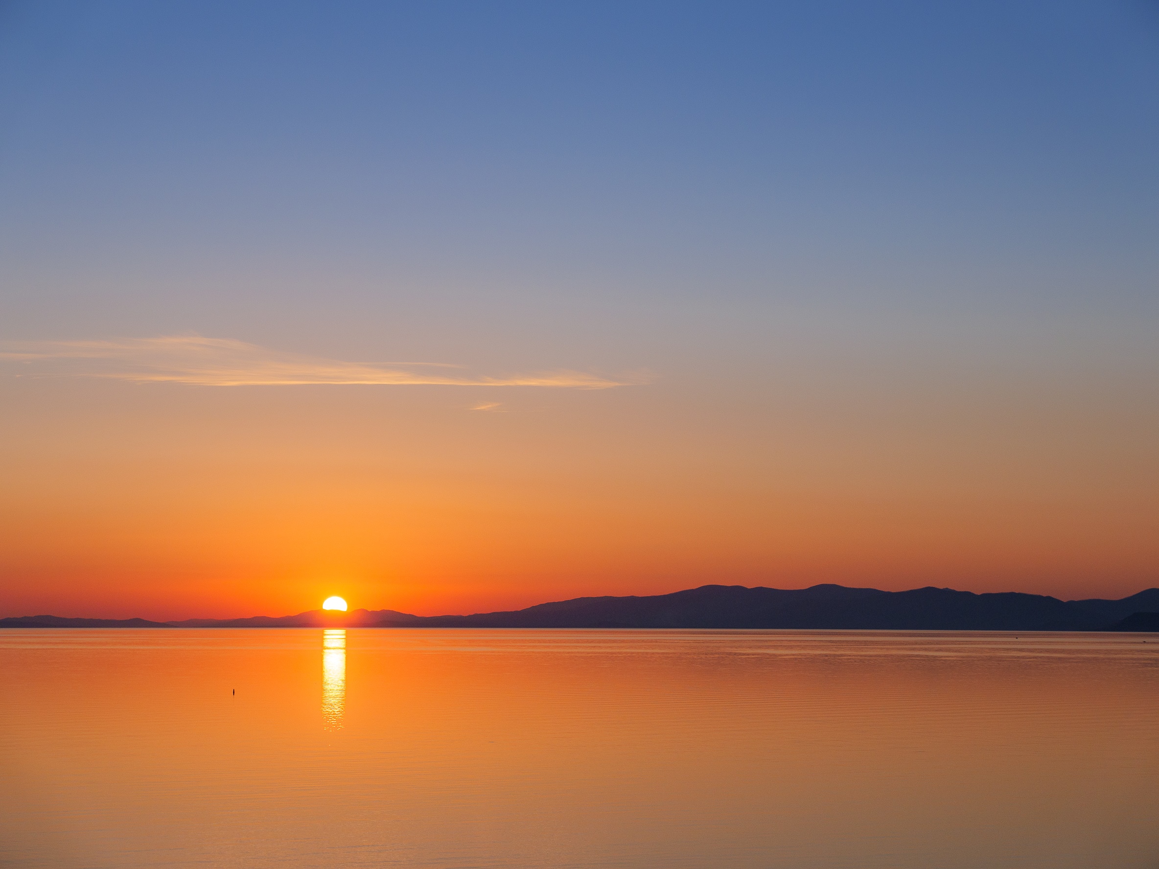 Sunset over the sea with mountains in the background HD Wallpaper