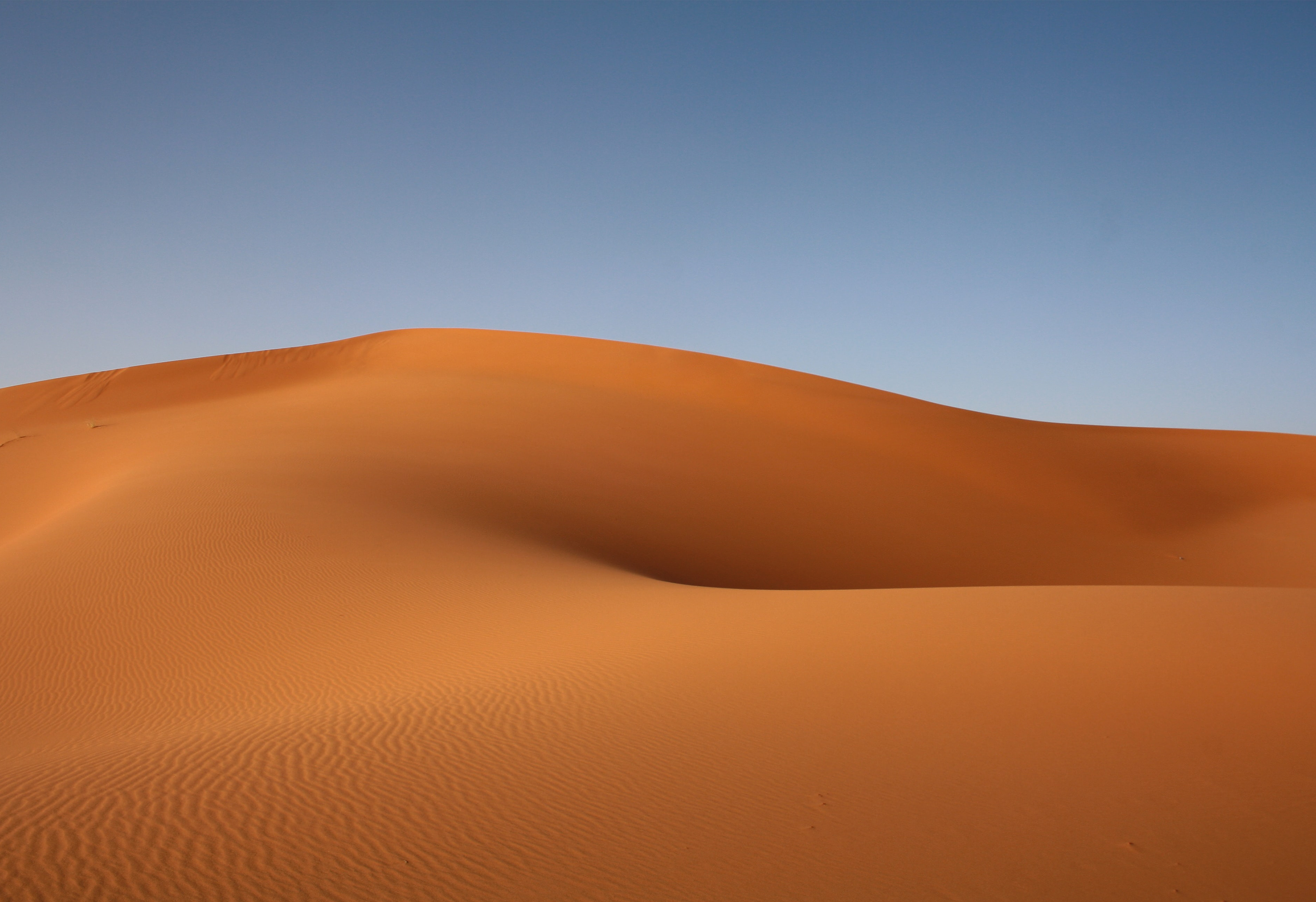 Vast desert sand dunes under a clear blue sky HD Wallpaper