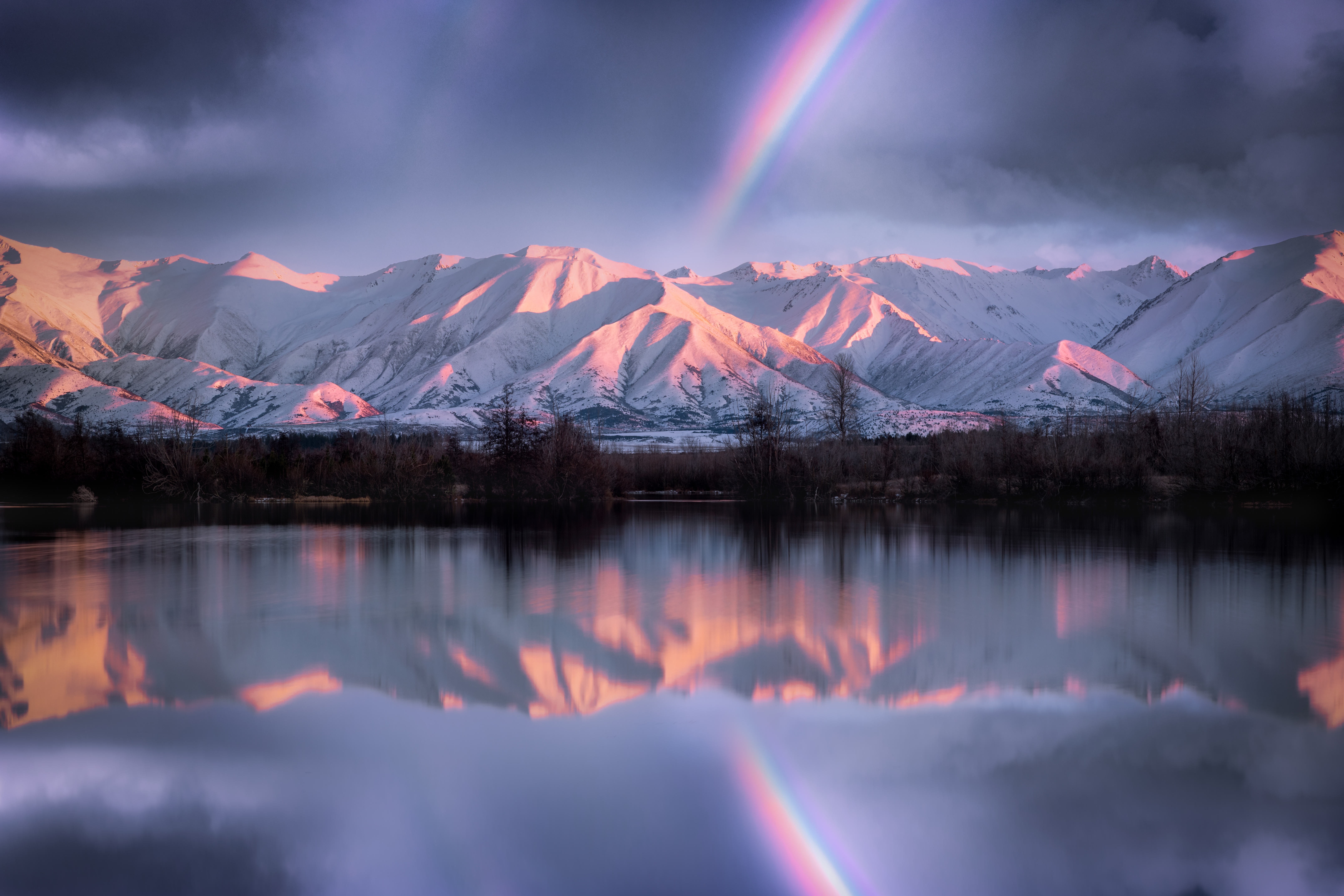 Snow-capped mountains reflected in a lake with a rainbow HD Wallpaper