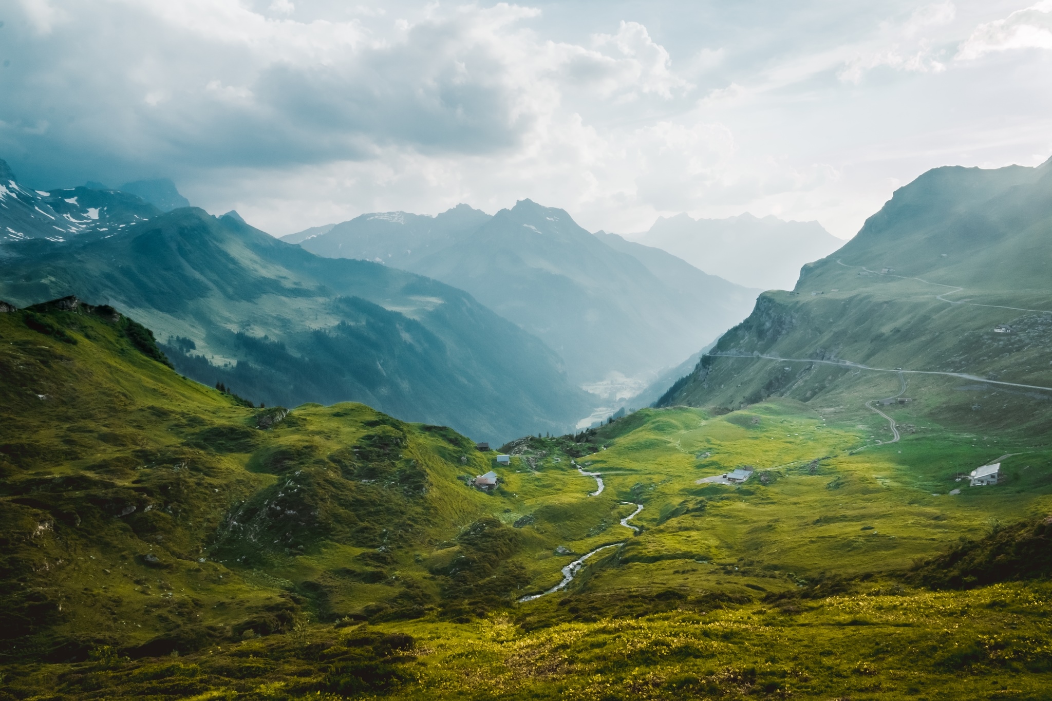 Green mountains with a winding stream and houses HD Wallpaper