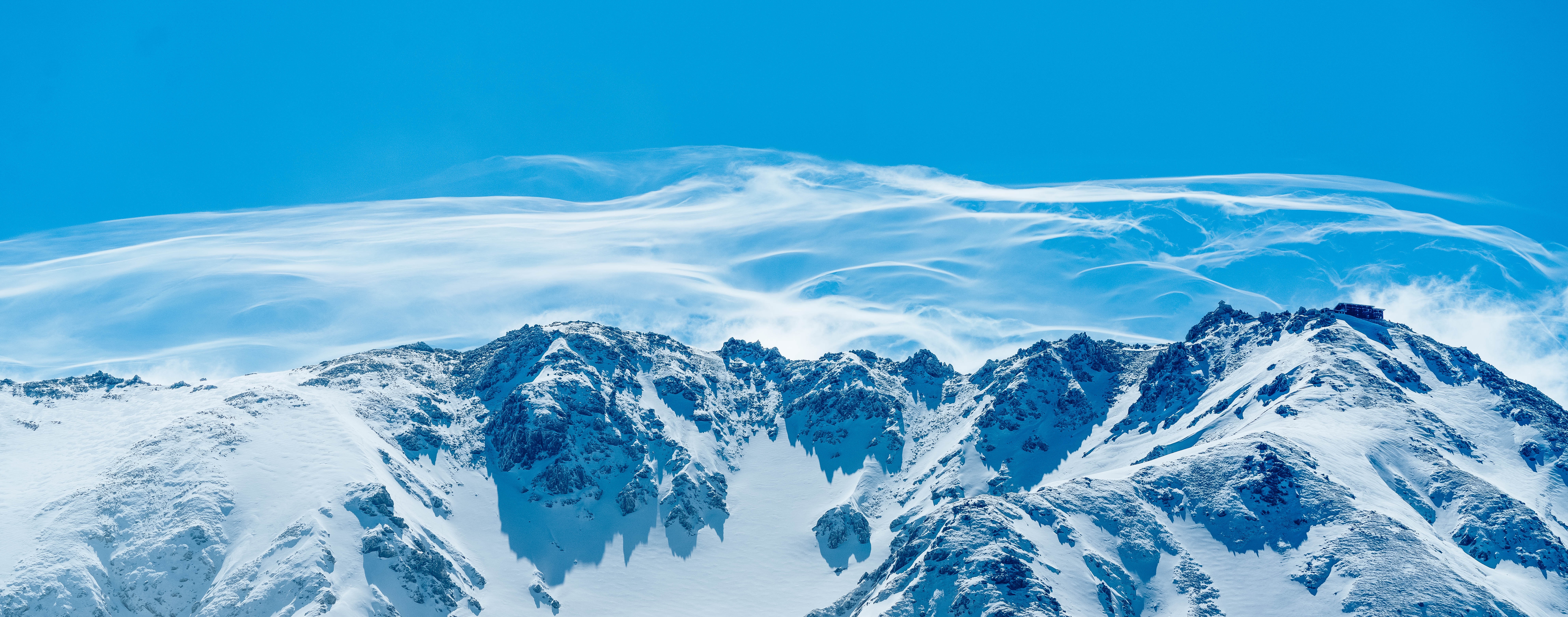 4K snow-covered mountains with wind-blown clouds HD Wallpaper