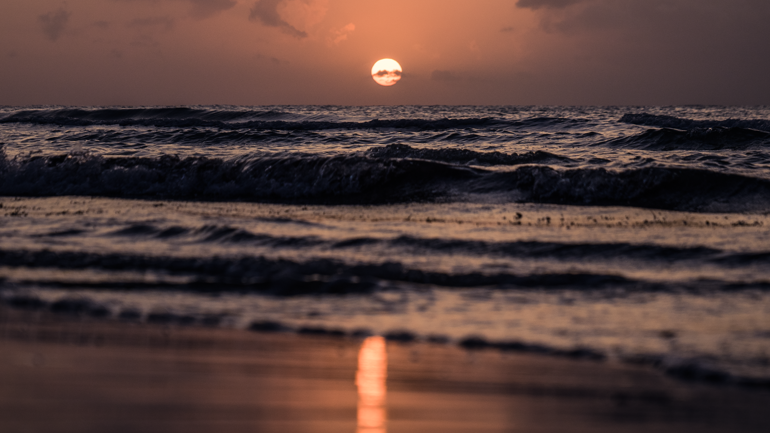 Sunset over the ocean with waves crashing on the shore HD Wallpaper