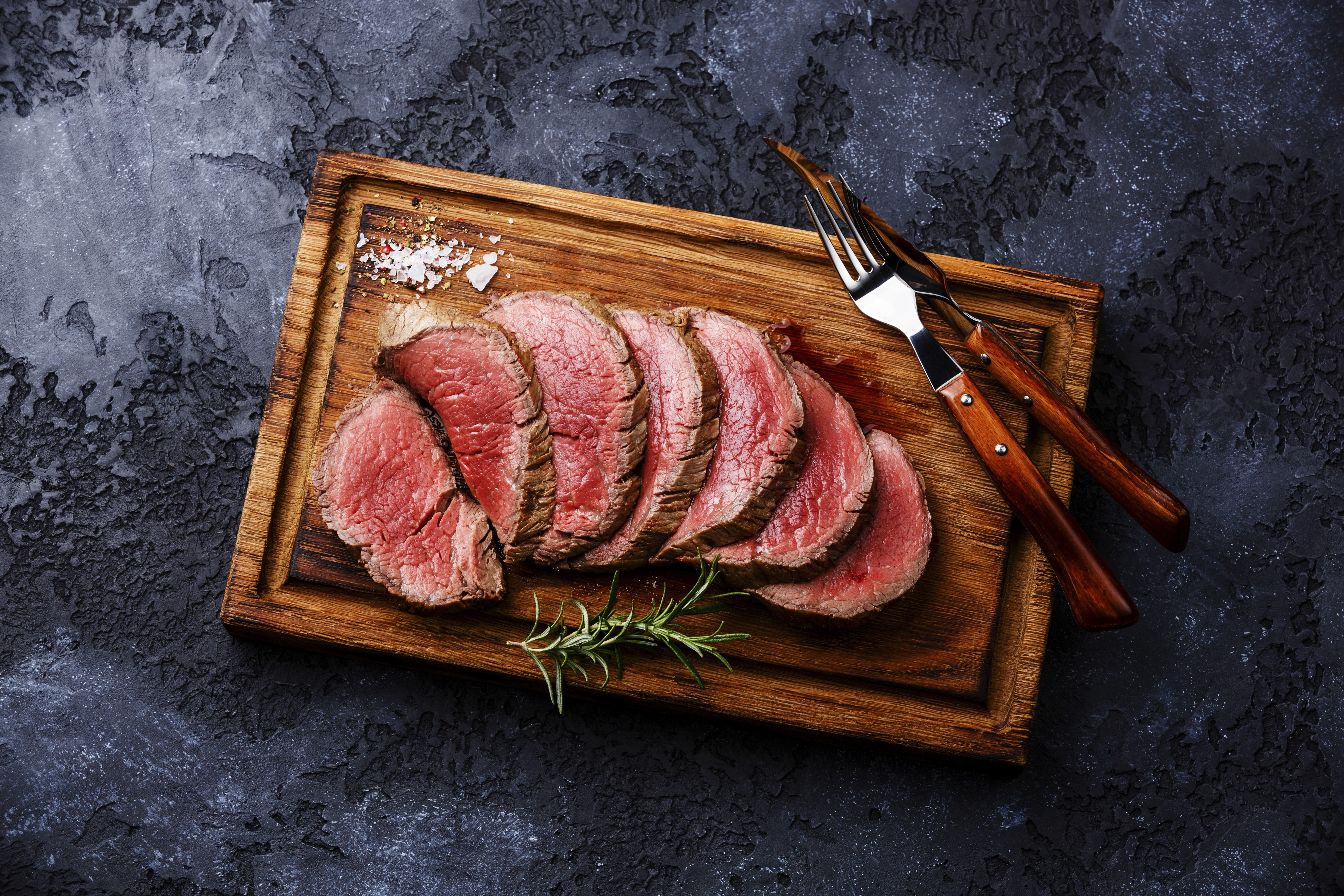 Sliced roast beef on a wooden board with rosemary HD Wallpaper