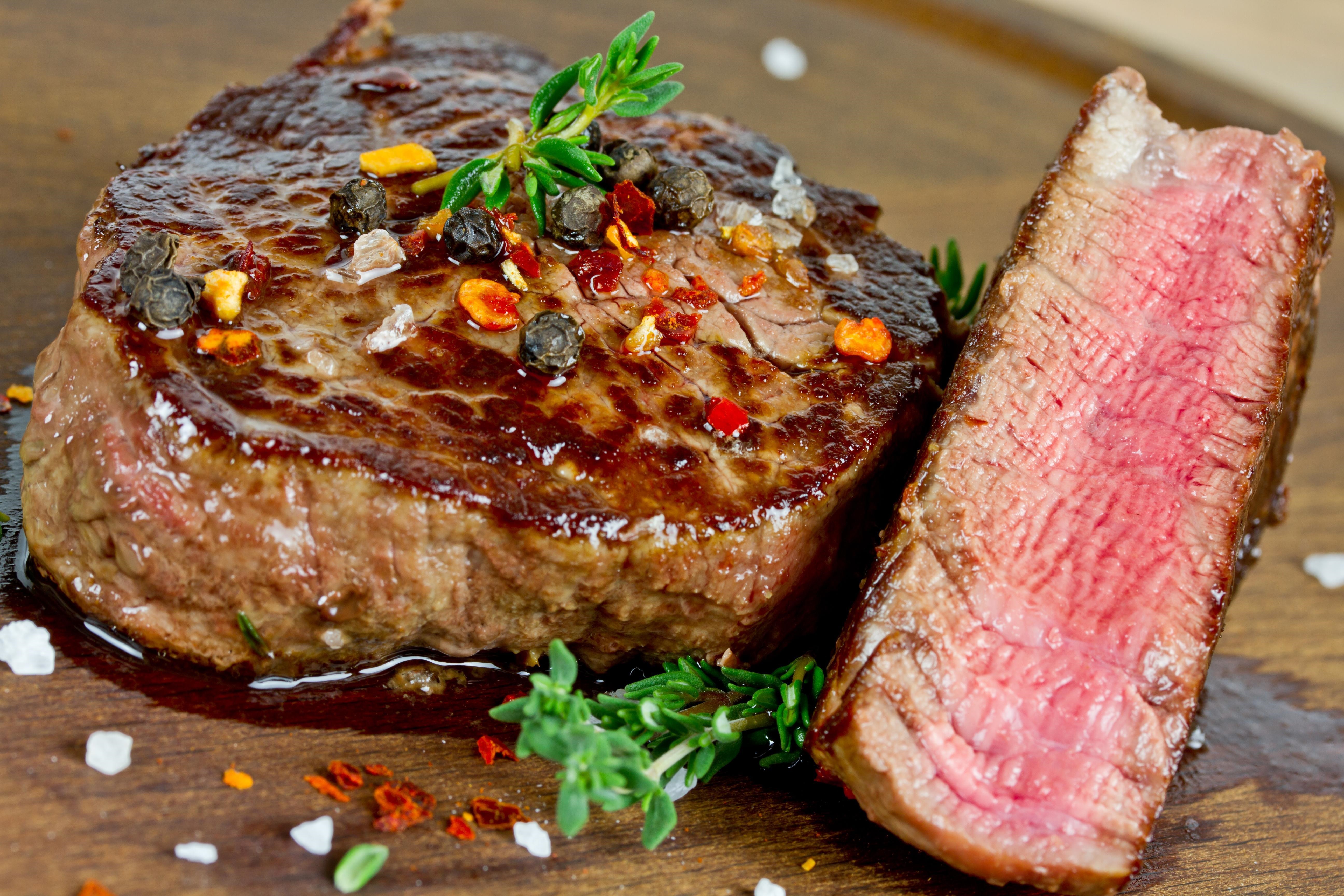 4K close-up of a seasoned steak with herbs HD Wallpaper