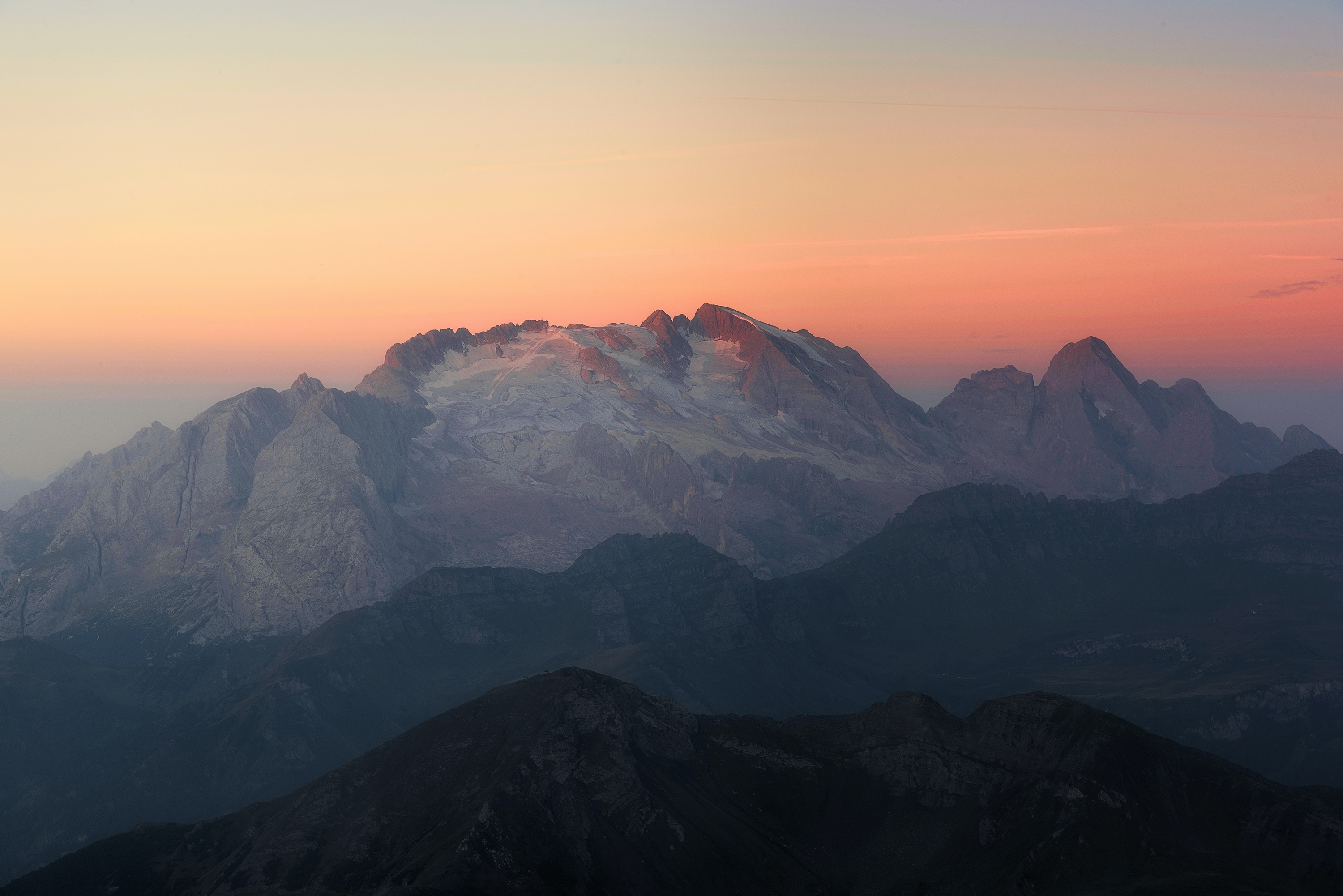 Snow-capped mountains at sunset with orange sky HD Wallpaper