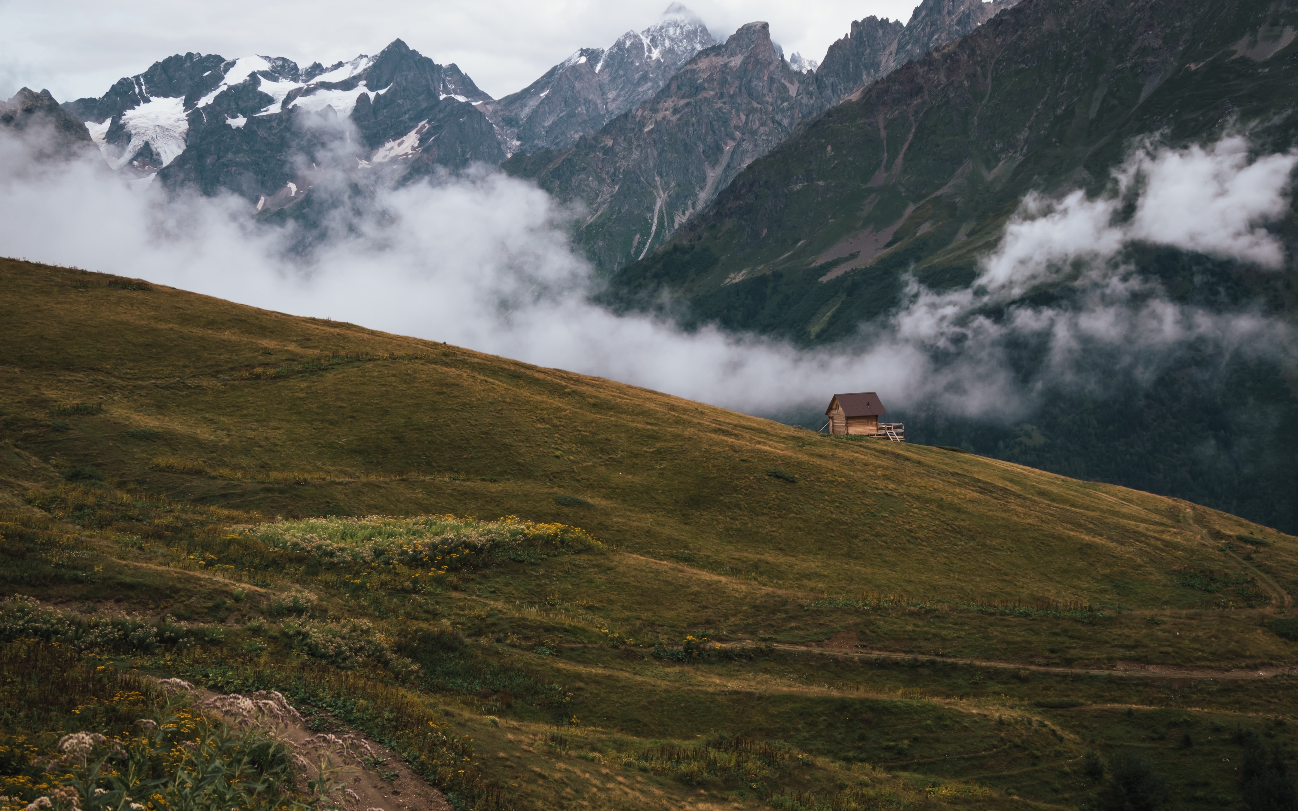4K mountains with clouds and a small cabin HD Wallpaper
