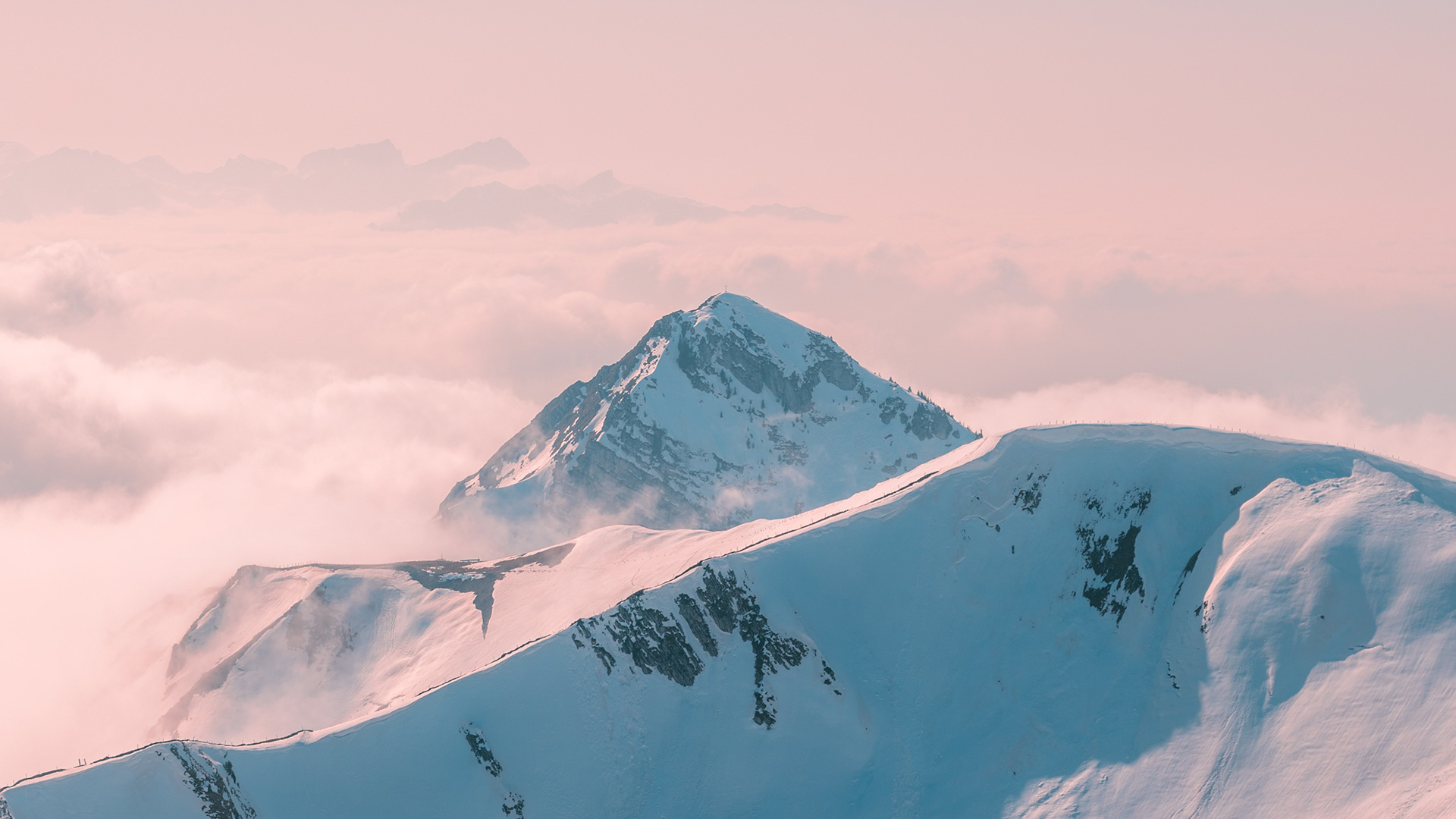 Snowy mountain peaks above clouds at sunrise HD Wallpaper