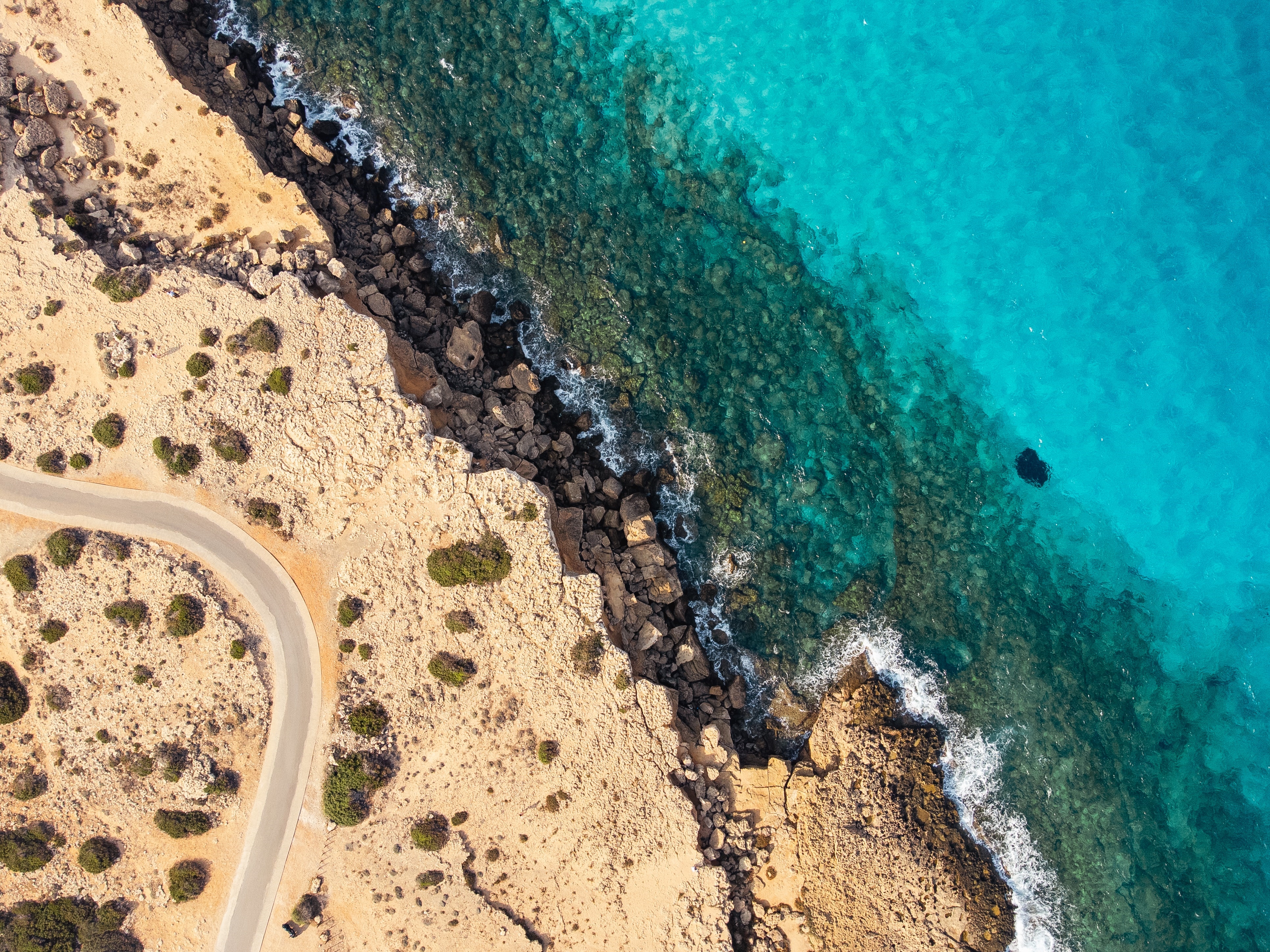 Aerial view of a rocky coast and turquoise water HD Wallpaper