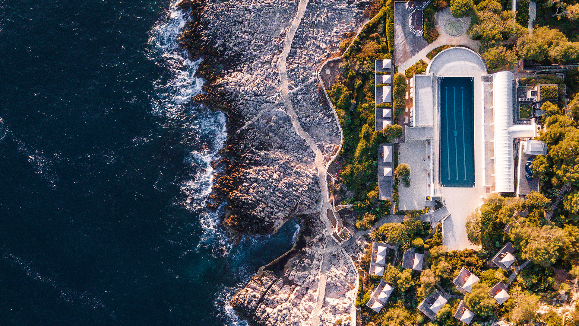 Aerial view of a coastal resort with a swimming pool HD Wallpaper
