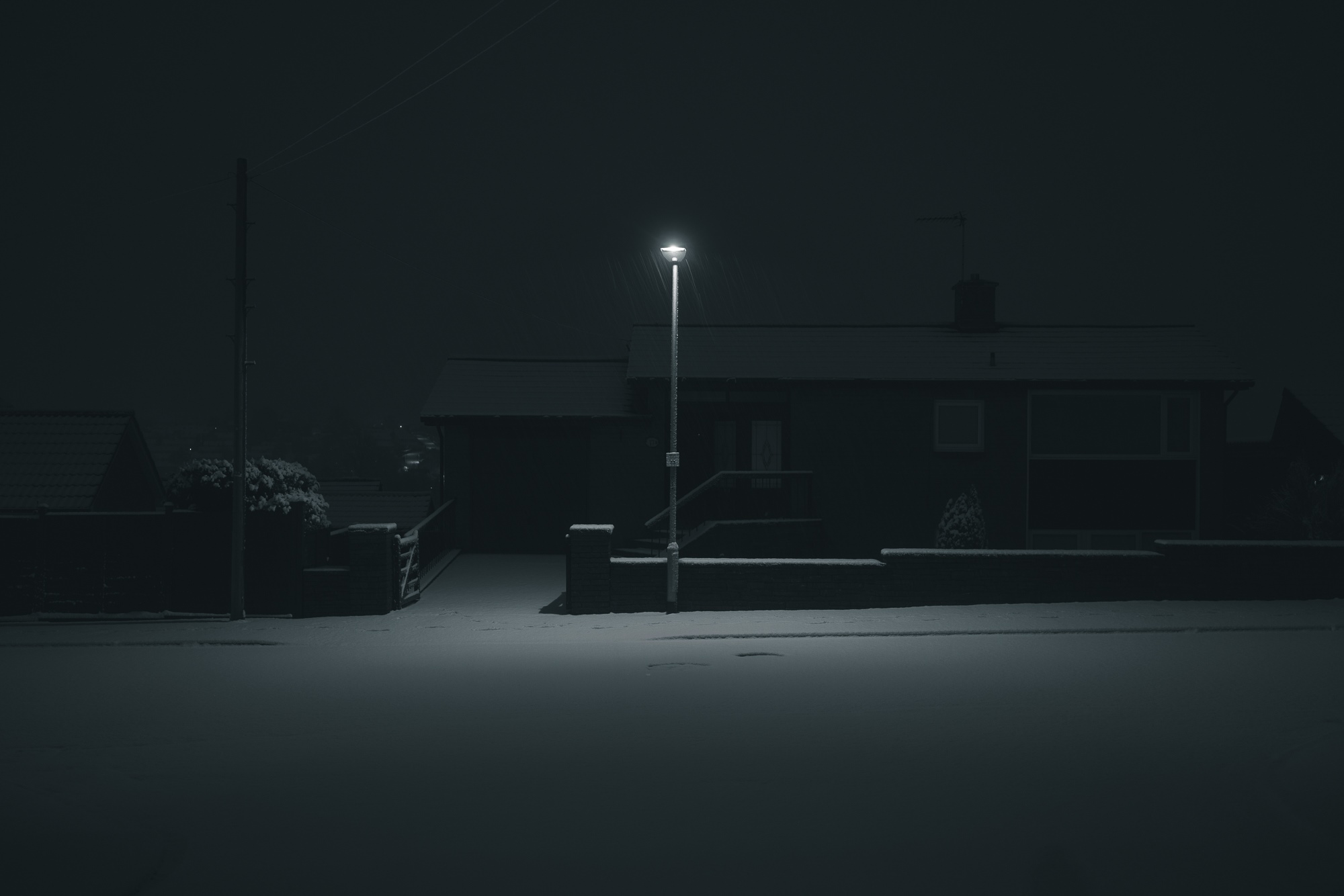 A house at night with a street light in the snow HD Wallpaper