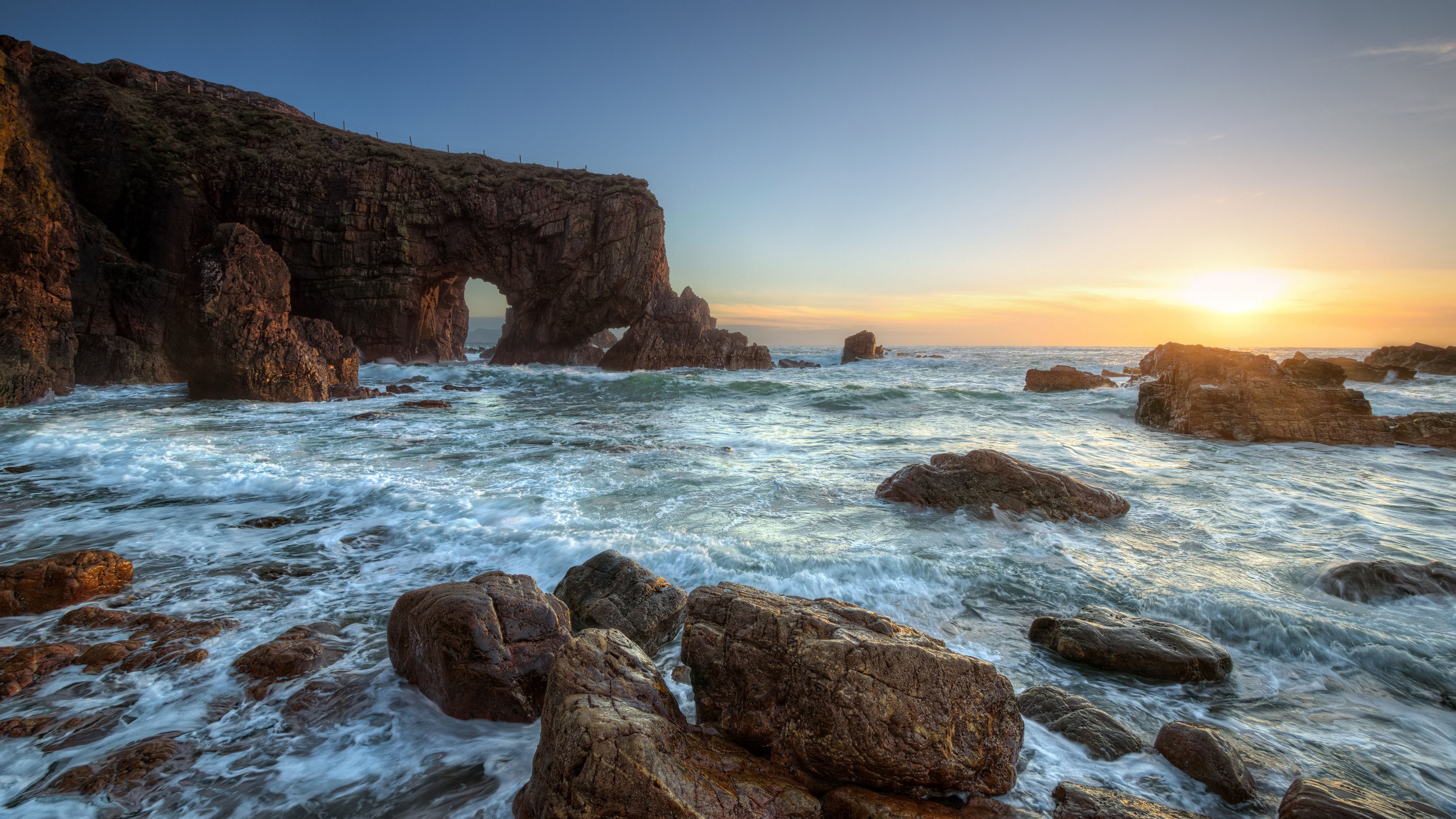 4K sunrise over rocky coast with sea arch HD Wallpaper