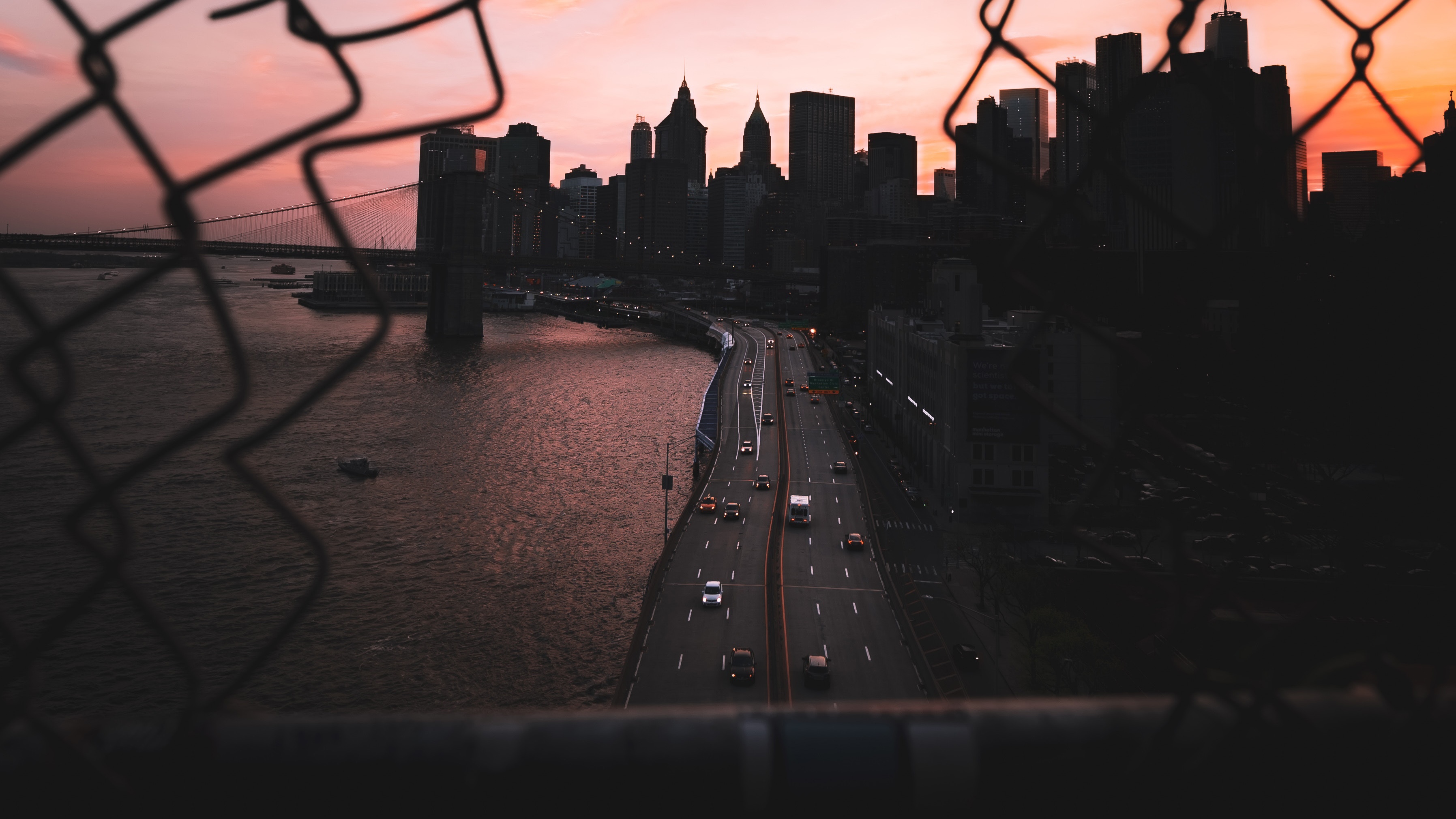 New York City skyline and highway at dusk through a fence HD Wallpaper
