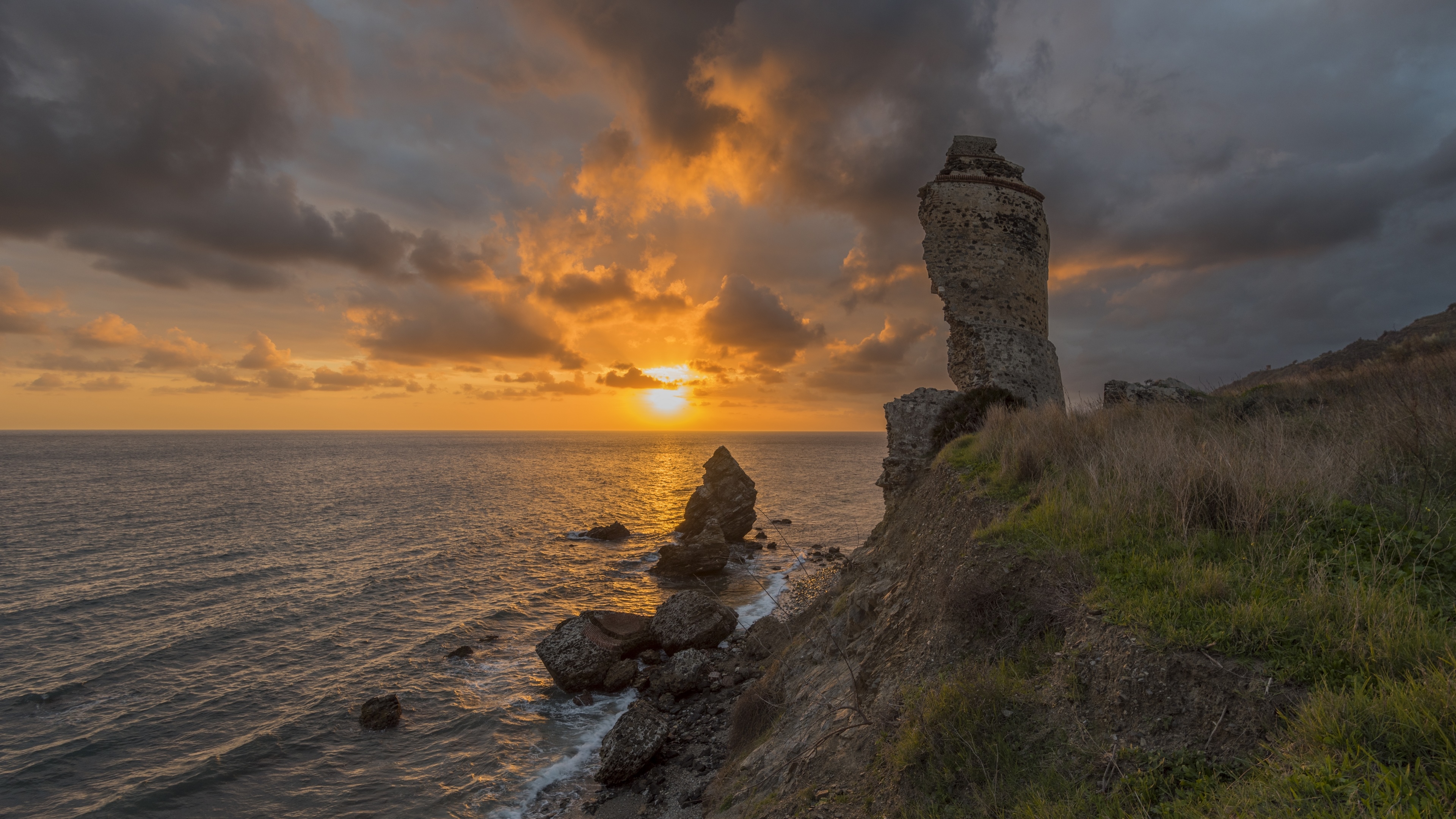 Sunset over the sea with rocks and ruins HD Wallpaper