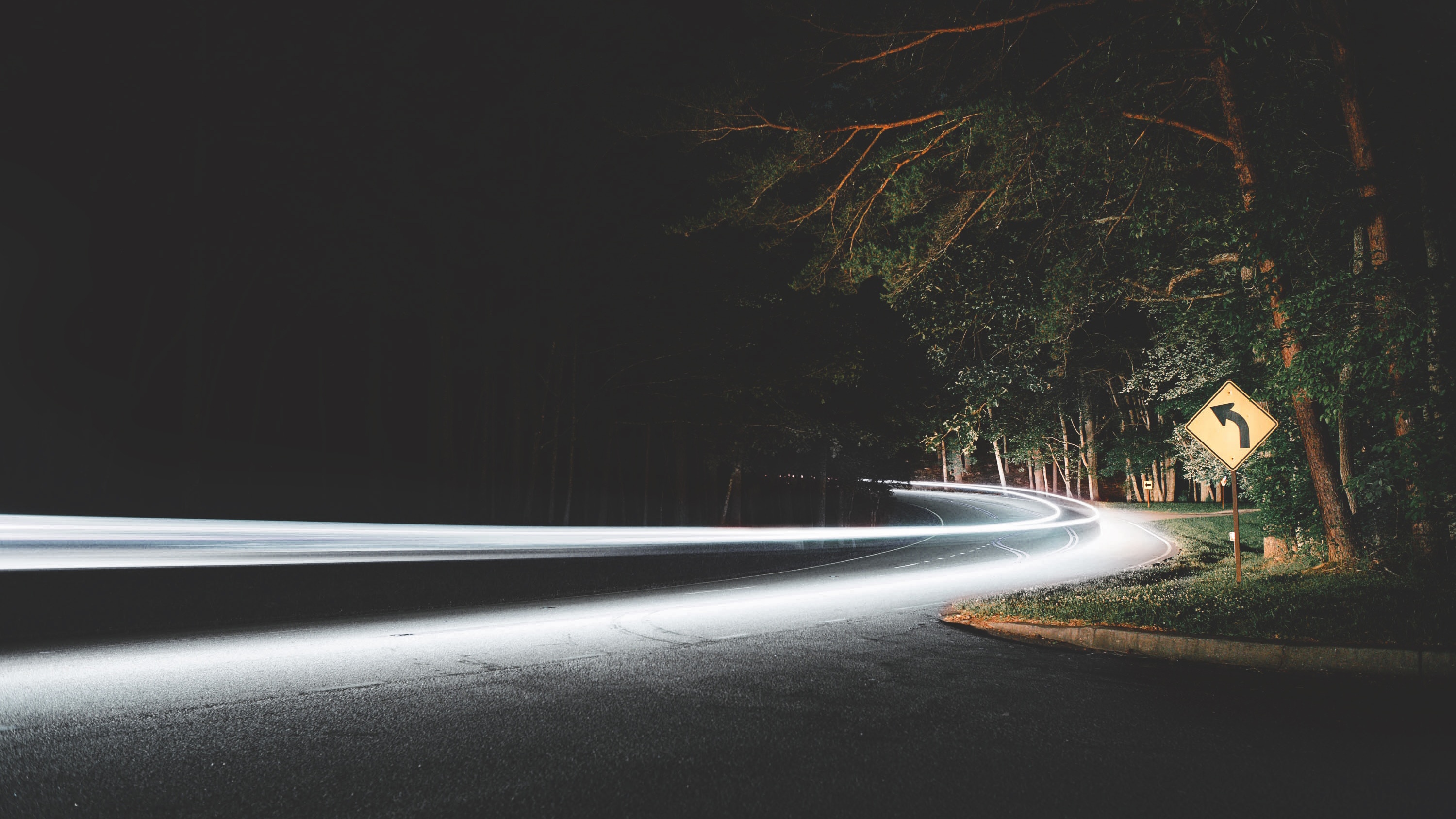 Long exposure of headlights on a winding road at night HD Wallpaper