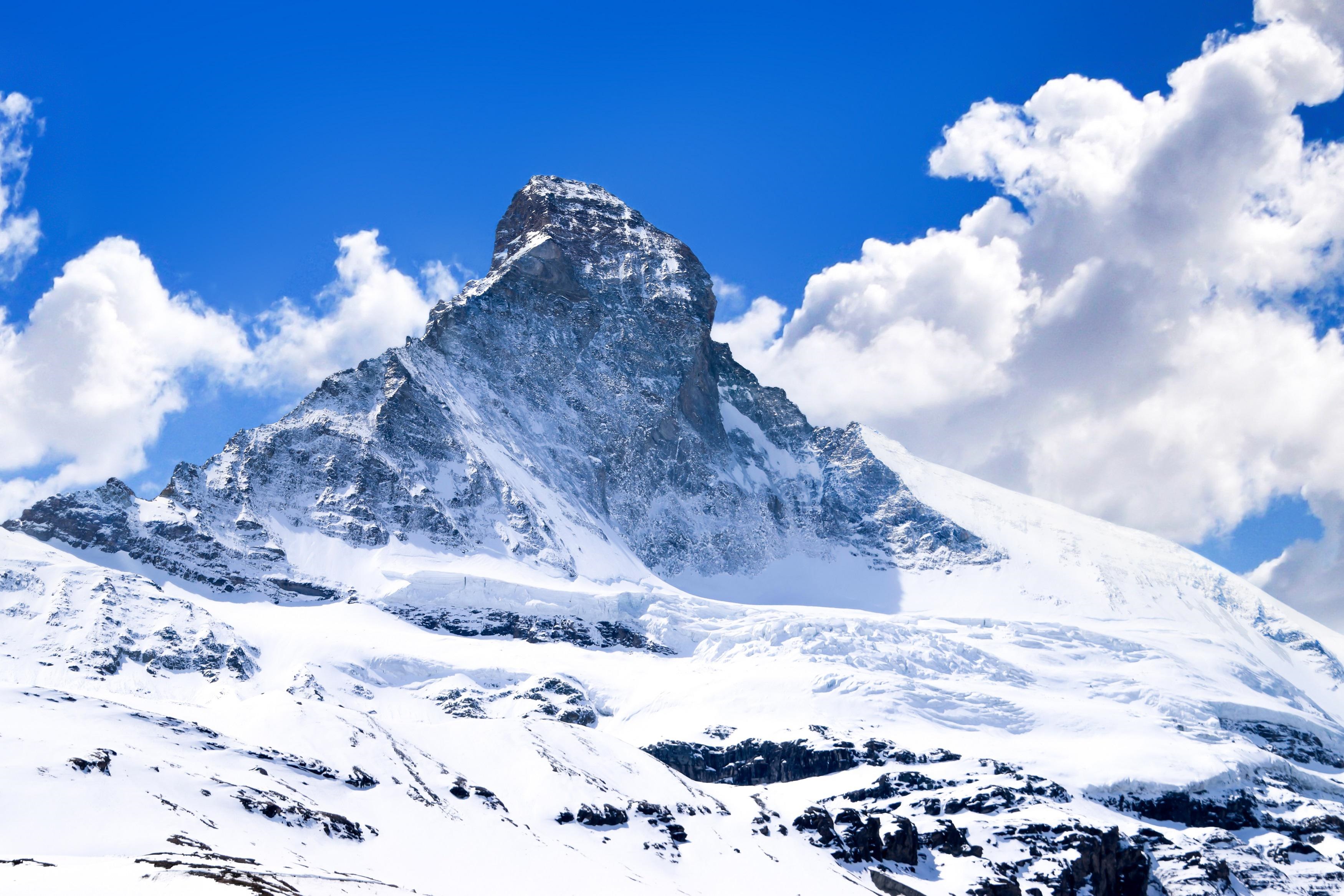 The Matterhorn mountain covered in snow under a blue sky with clouds HD Wallpaper