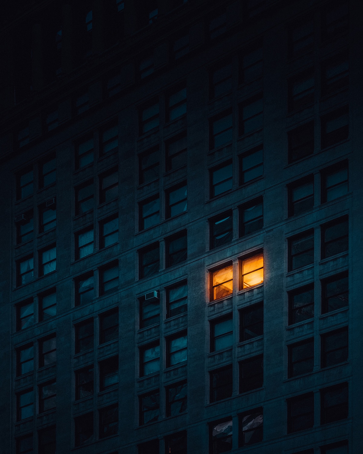 Building with one lit window at night HD Phone Wallpaper