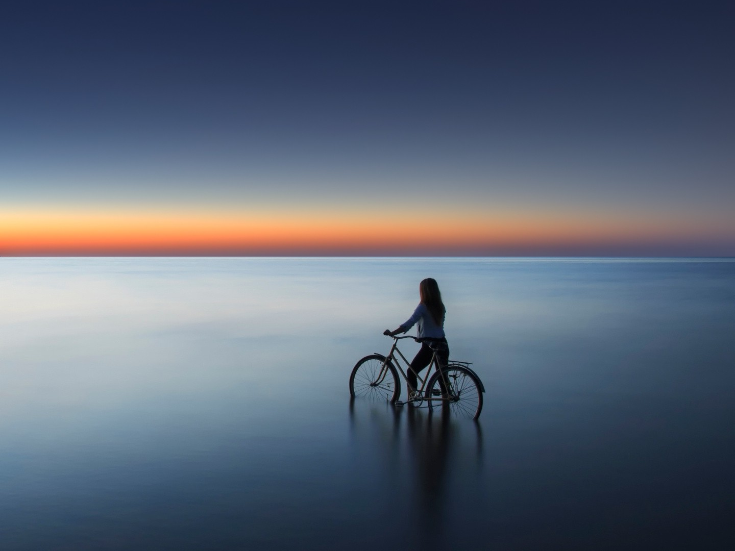 Woman on a bicycle at dusk by the sea in Latvia HD Wallpaper