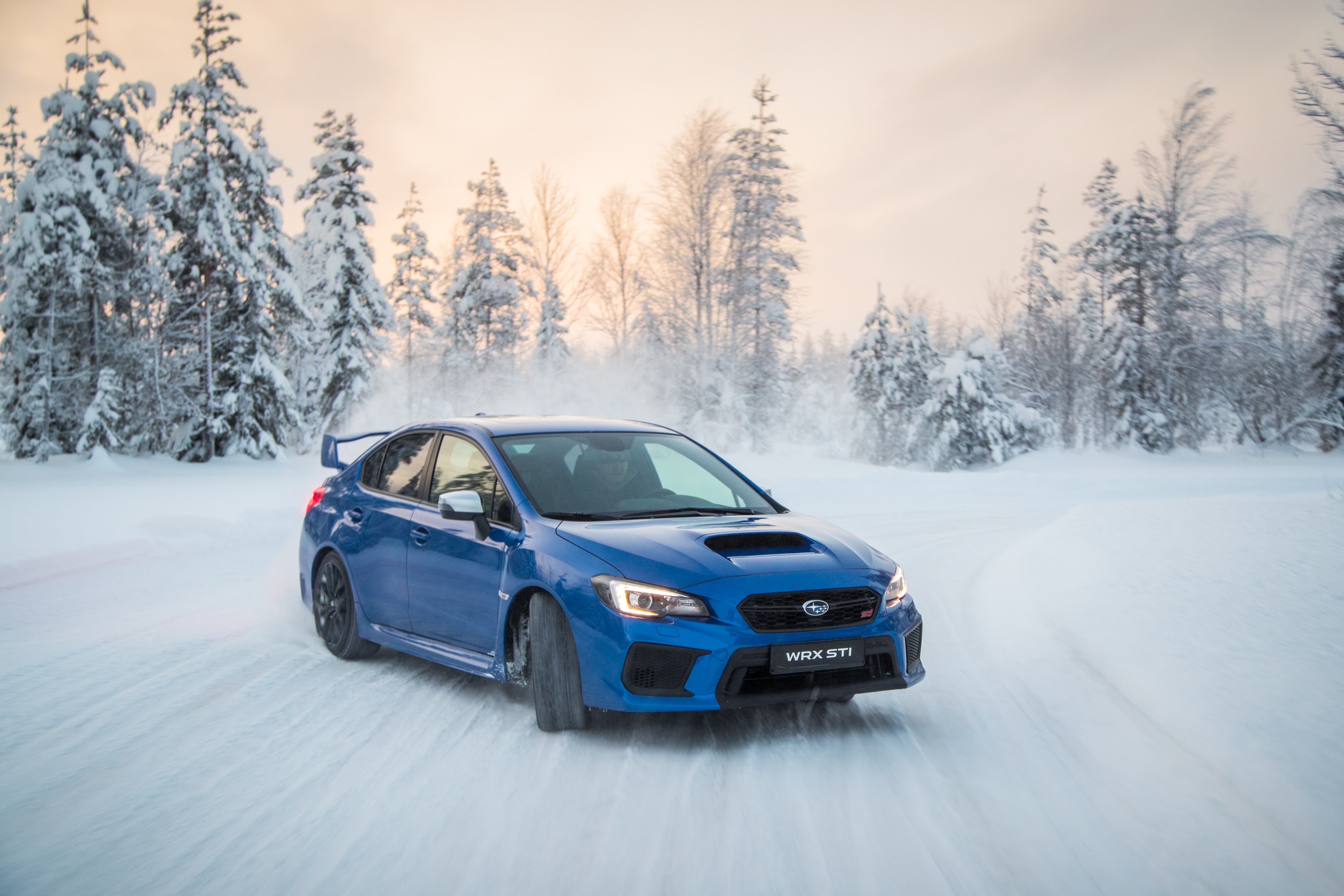 Blue Subaru WRX STI driving on a snowy road HD Wallpaper